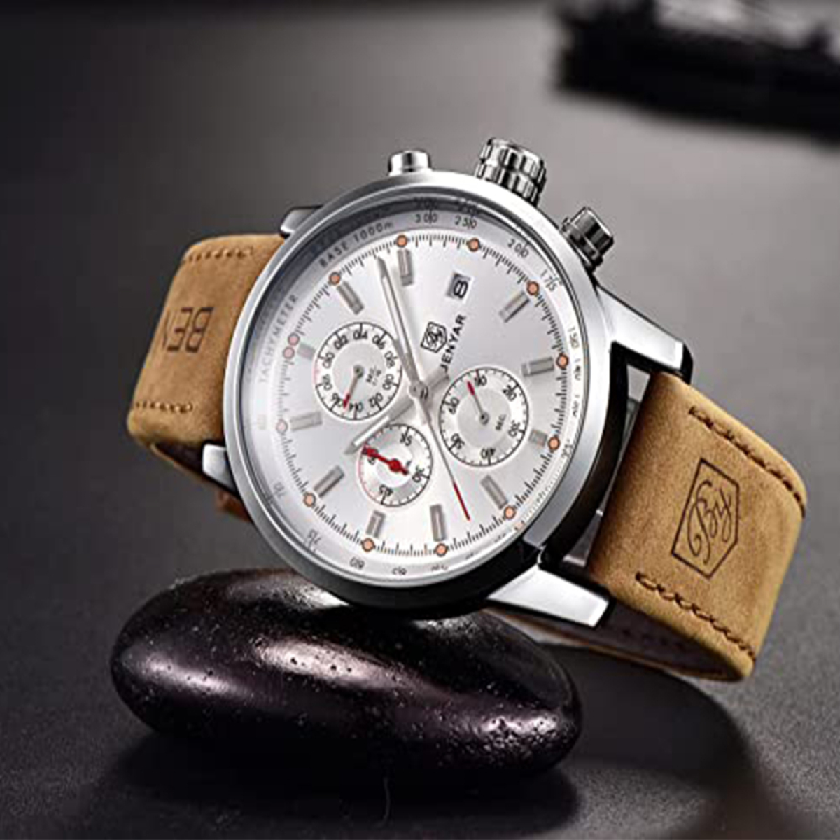 Silberne und braune Uhr auf einem schwarzen Stein. Die Uhr hat ein weißes Zifferblatt und ein braunes Lederarmband.