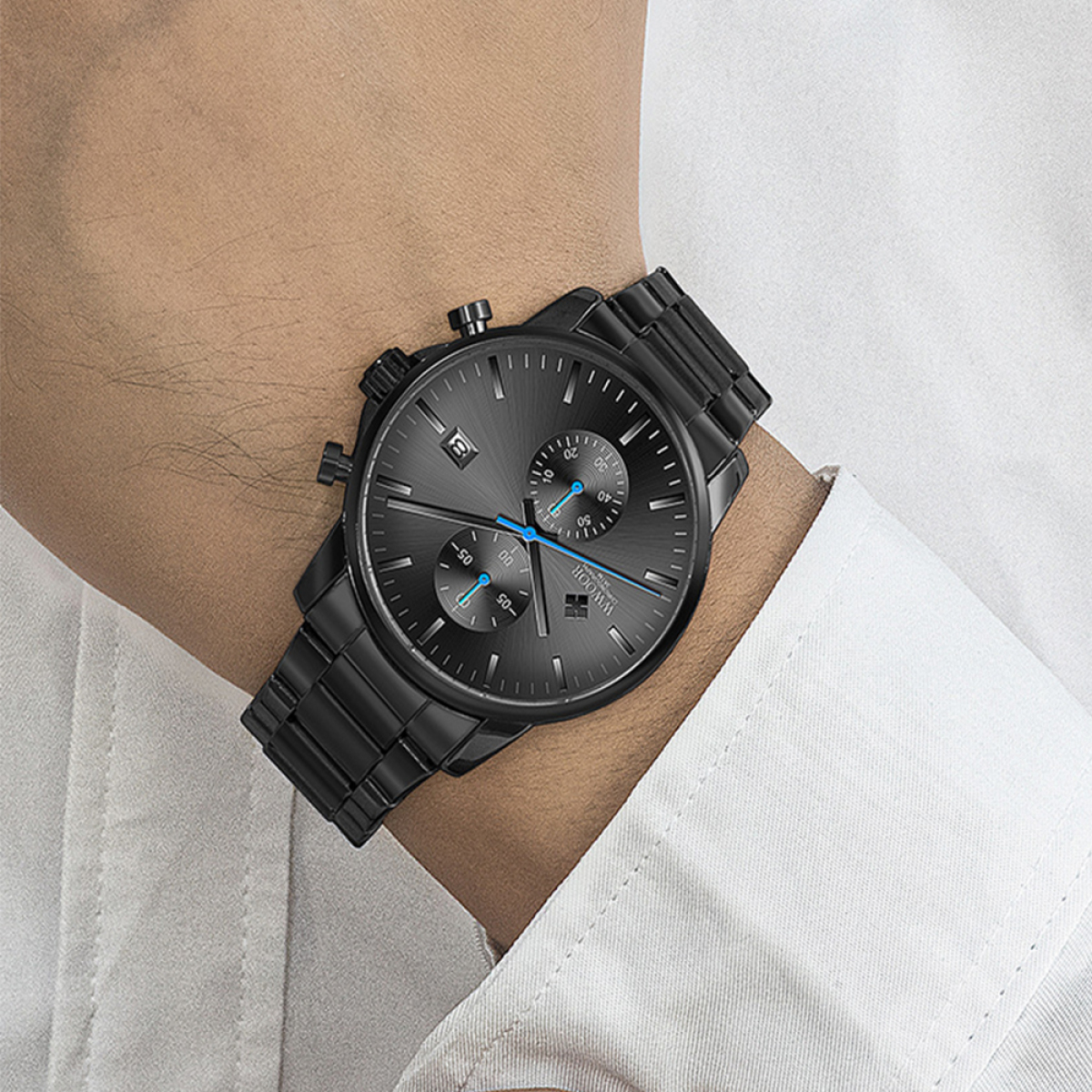 Eine schwarze Uhr am Handgelenk. Schwarzes Armband und Zifferblatt, blaue Akzente. Weißes Hemd.