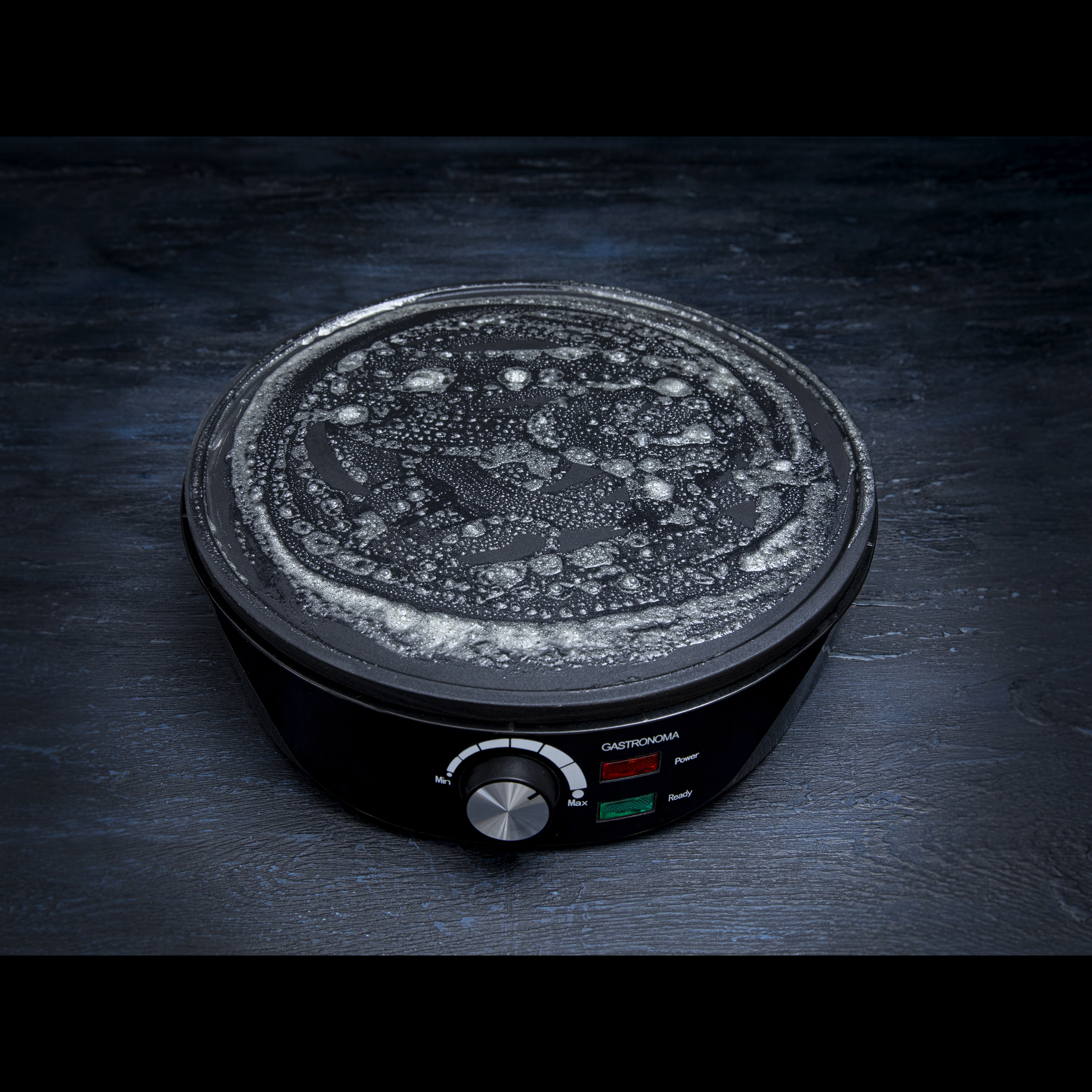 Czarna płyta do grillowania Gastronomia z pokrętłem i kontrolkami zasilania i gotowości. Powierzchnia ma pęcherzyki.