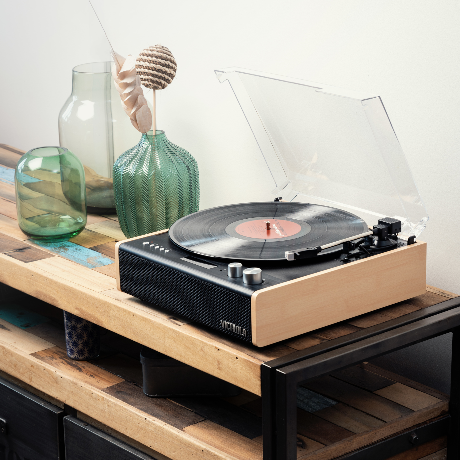 Un giradischi su un supporto in legno. Un disco in vinile sul piatto. Coperchio trasparente sollevato.
