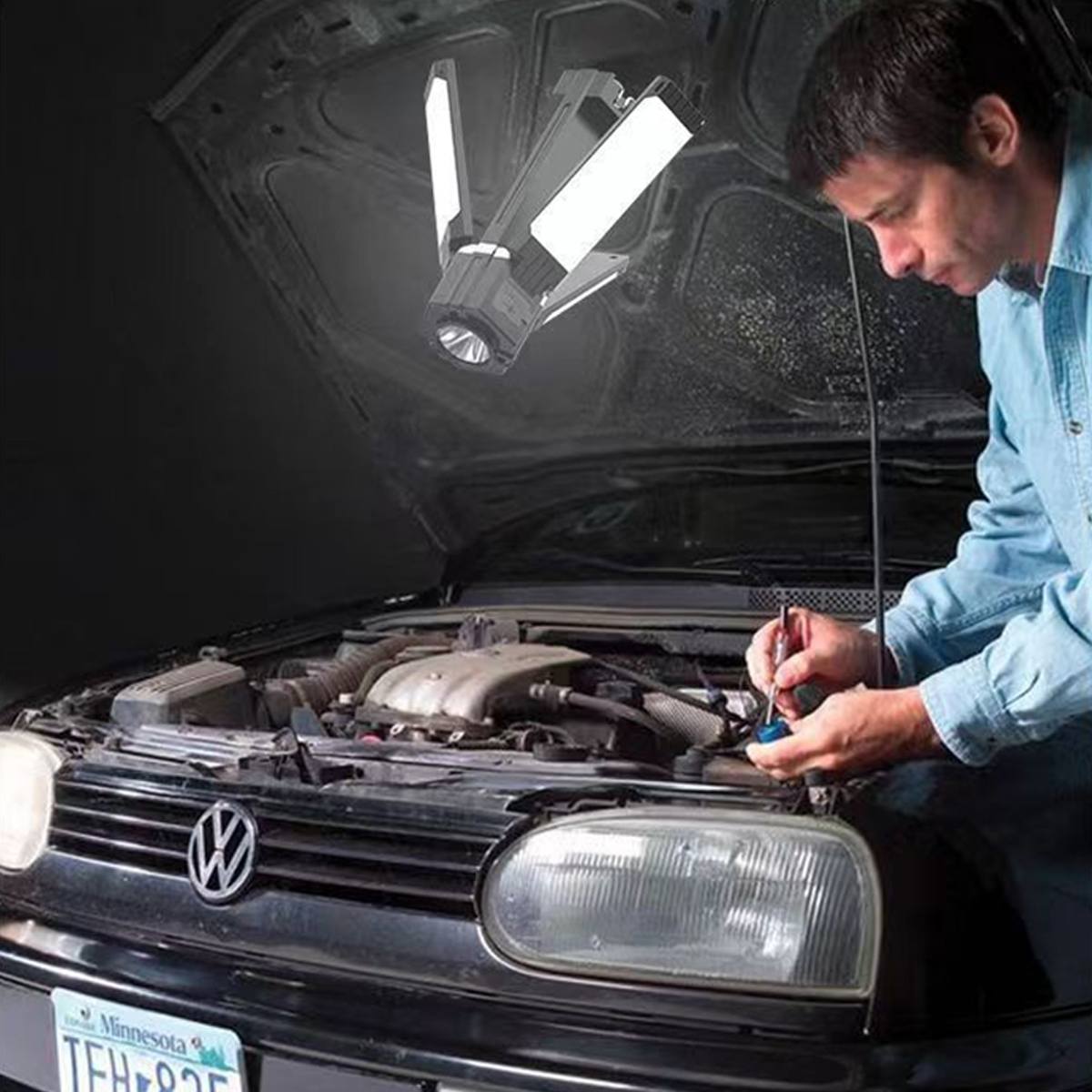 Mann arbeitet an einem Automotor unter einer hellen, verstellbaren LED-Arbeitsleuchte.