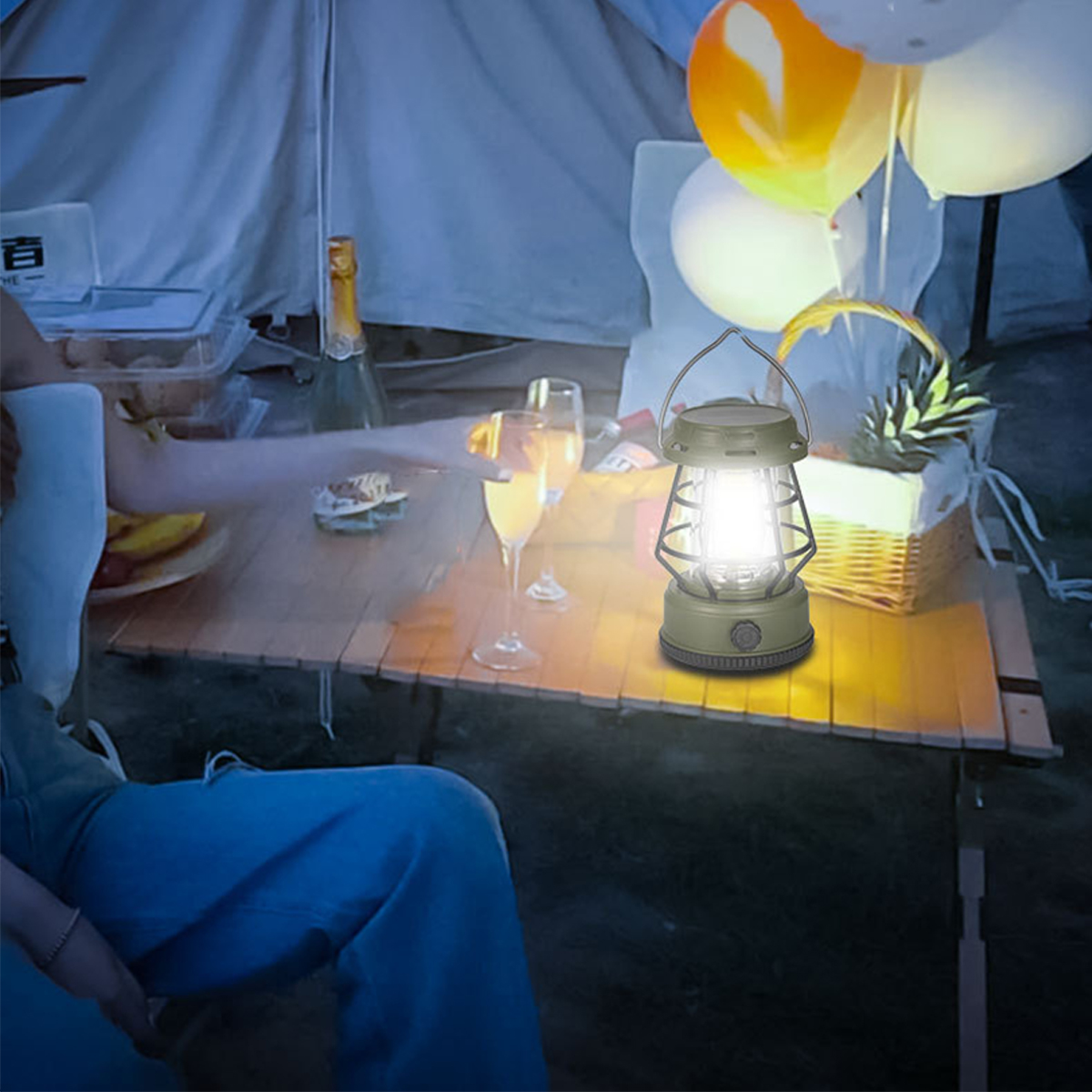 Eine beleuchtete Laterne auf einem Tisch mit Essen und Getränken. Ballons sind im Hintergrund.