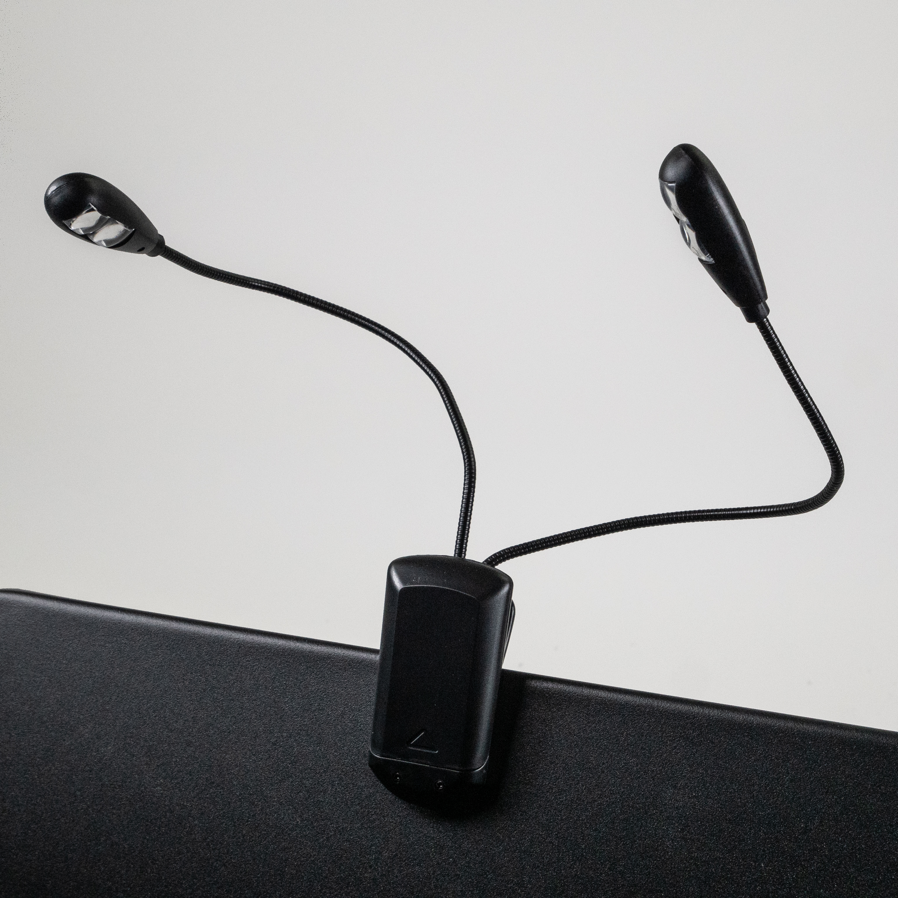 Zwei schwarze LED-Clip-On-Leuchten auf schwarzer Oberfläche.