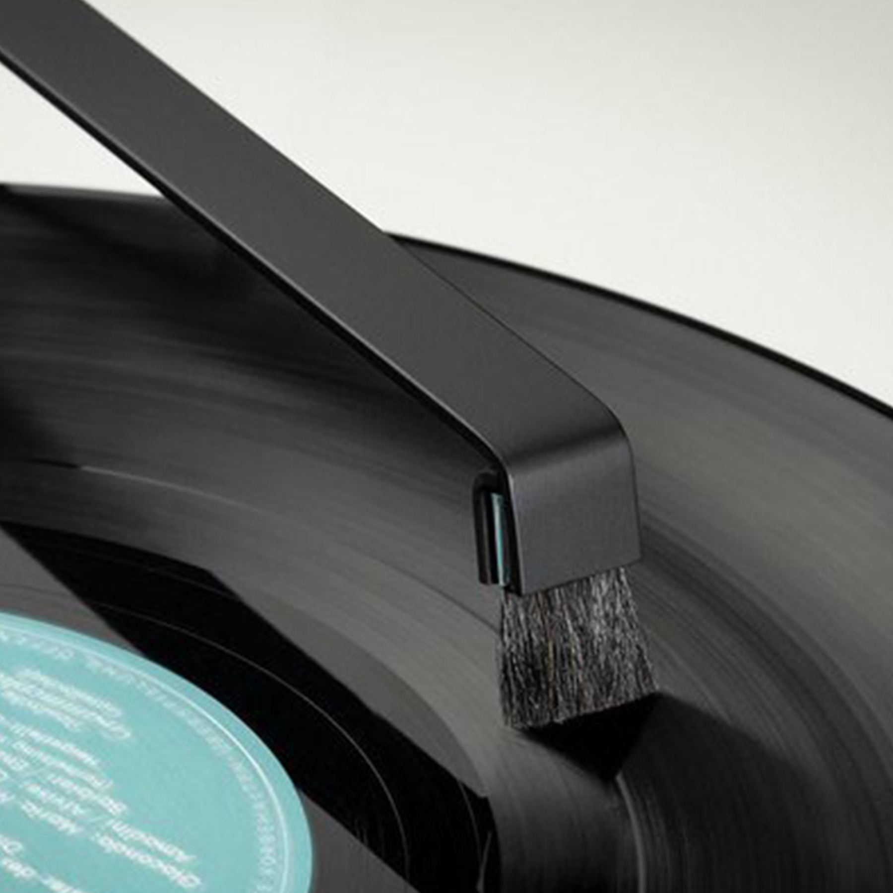 Czarna szczotka do płyt czyszcząca czarną płytę winylową, z jasnym tłem.