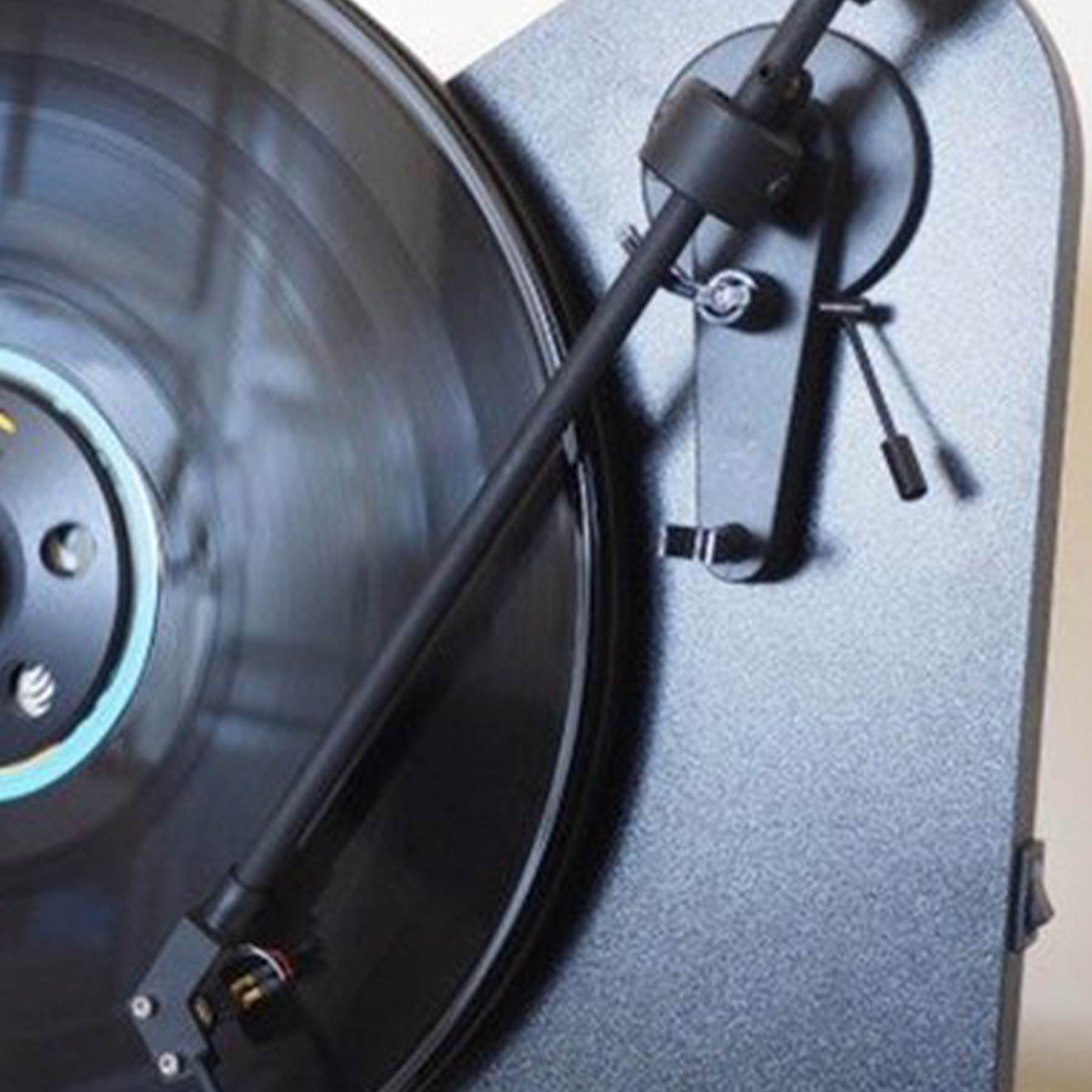 Een close-up van een platenspeler met een draaiende zwarte vinylplaat. De toonarm is zichtbaar.