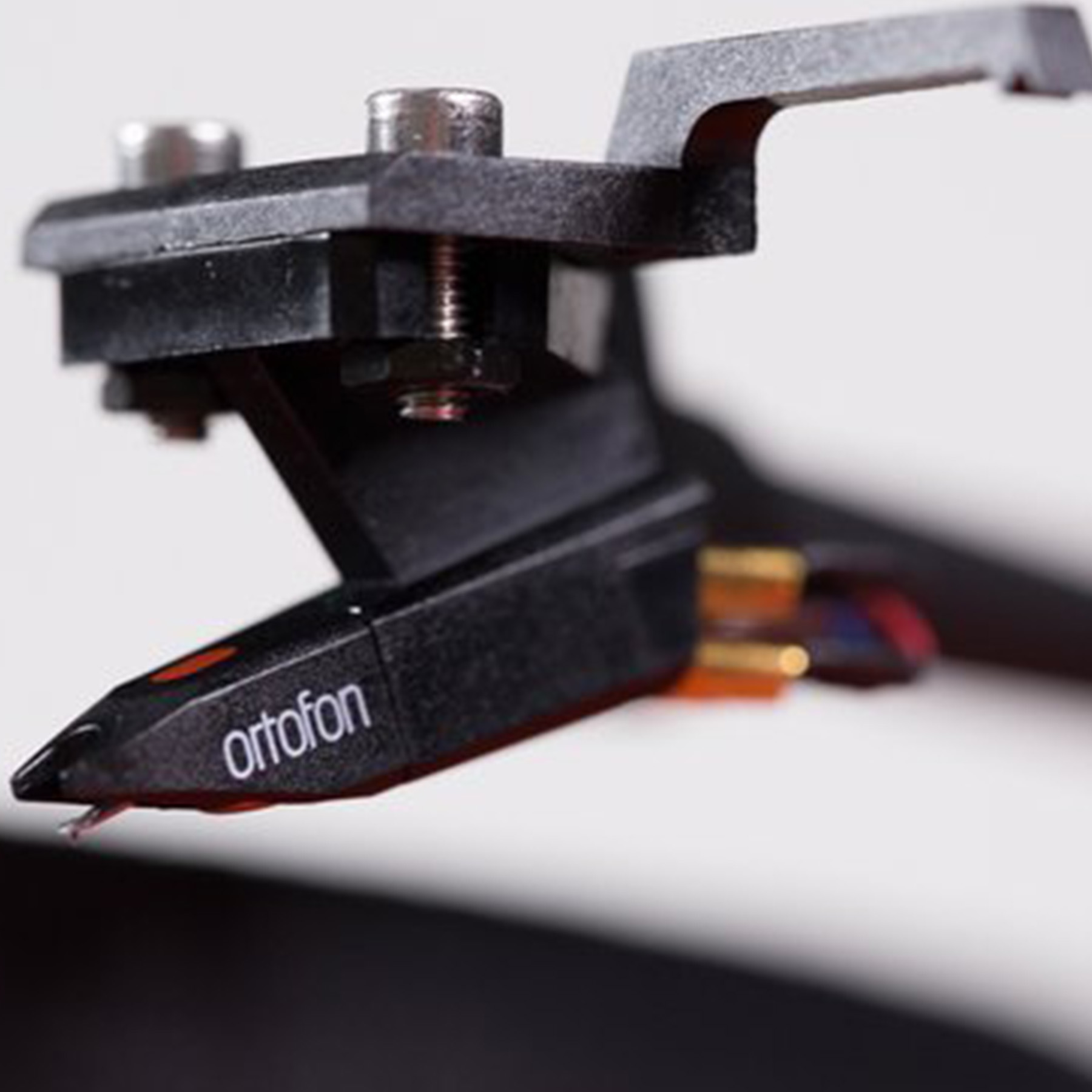 Zbliżenie czarnego wkładu fonograficznego z logo ortofon i czerwoną igłą.