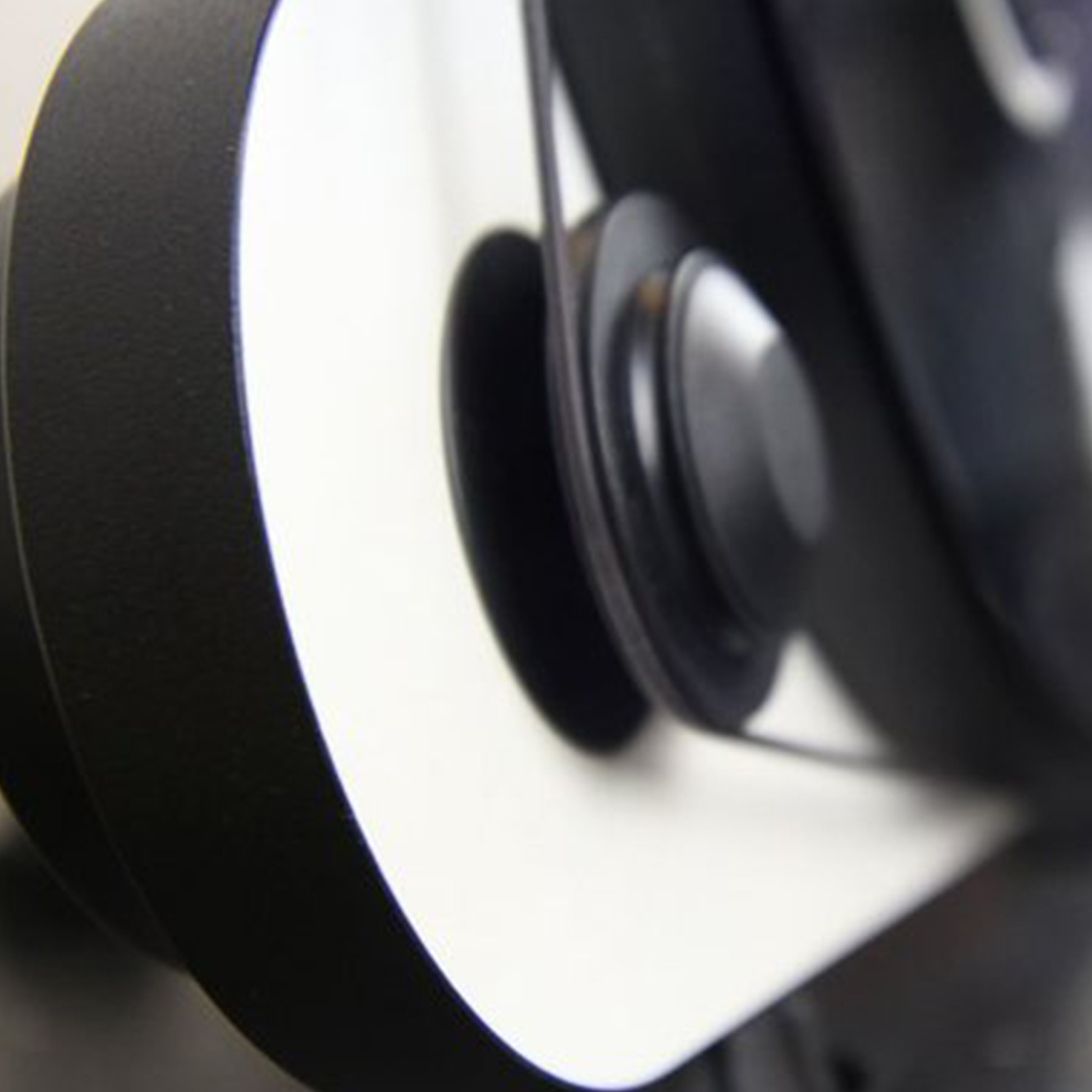 Zbliżenie czarnego elementu bieżni z paskiem i rolką. Białe tło.