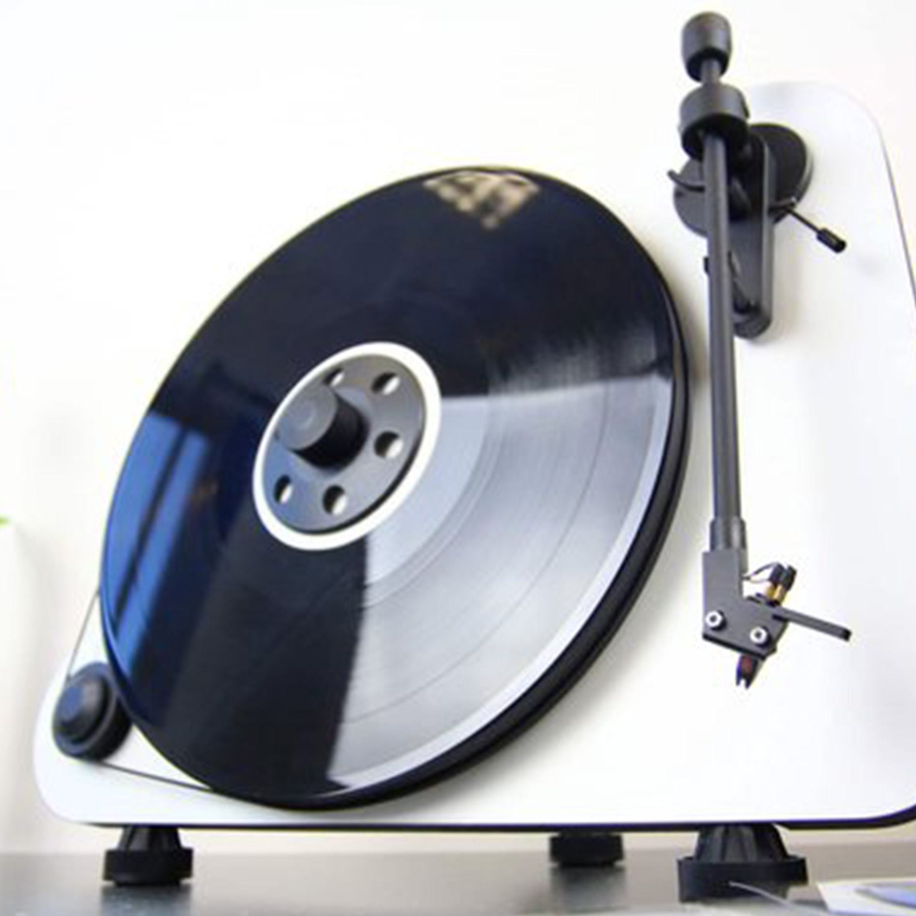 Gramofon z czarną płytą winylową na białej powierzchni.