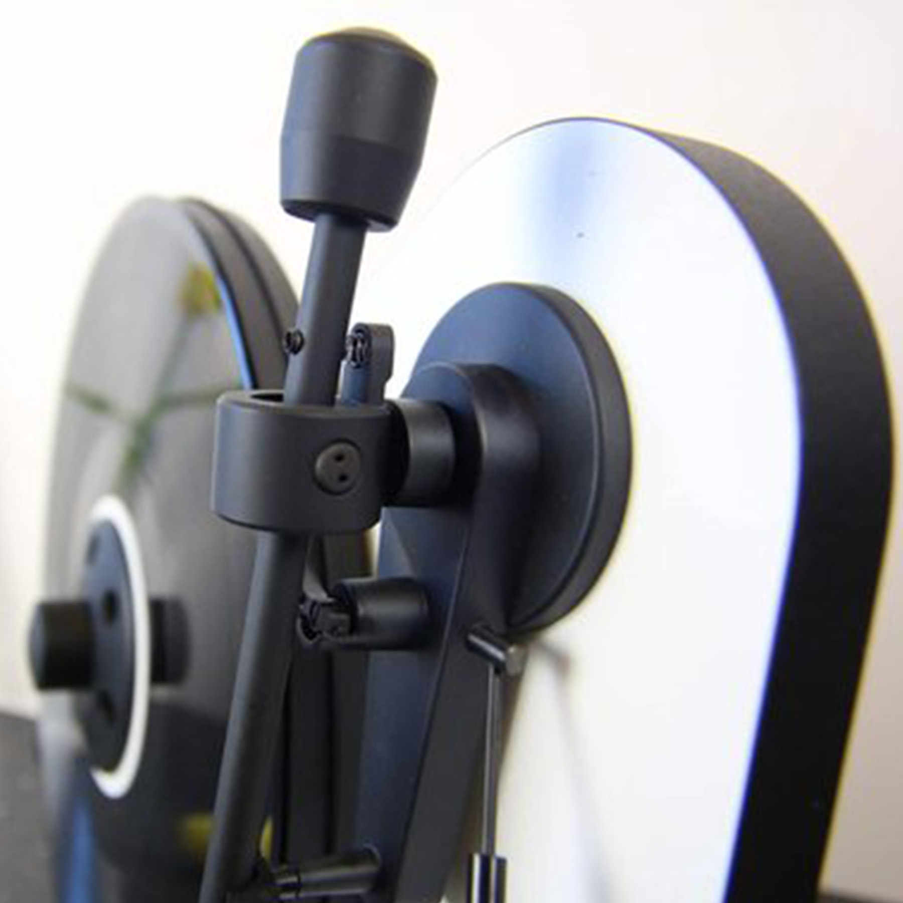 Zbliżenie dwóch ciemnych dysków z czarnymi trzonami i białym okrągłym wzorem.