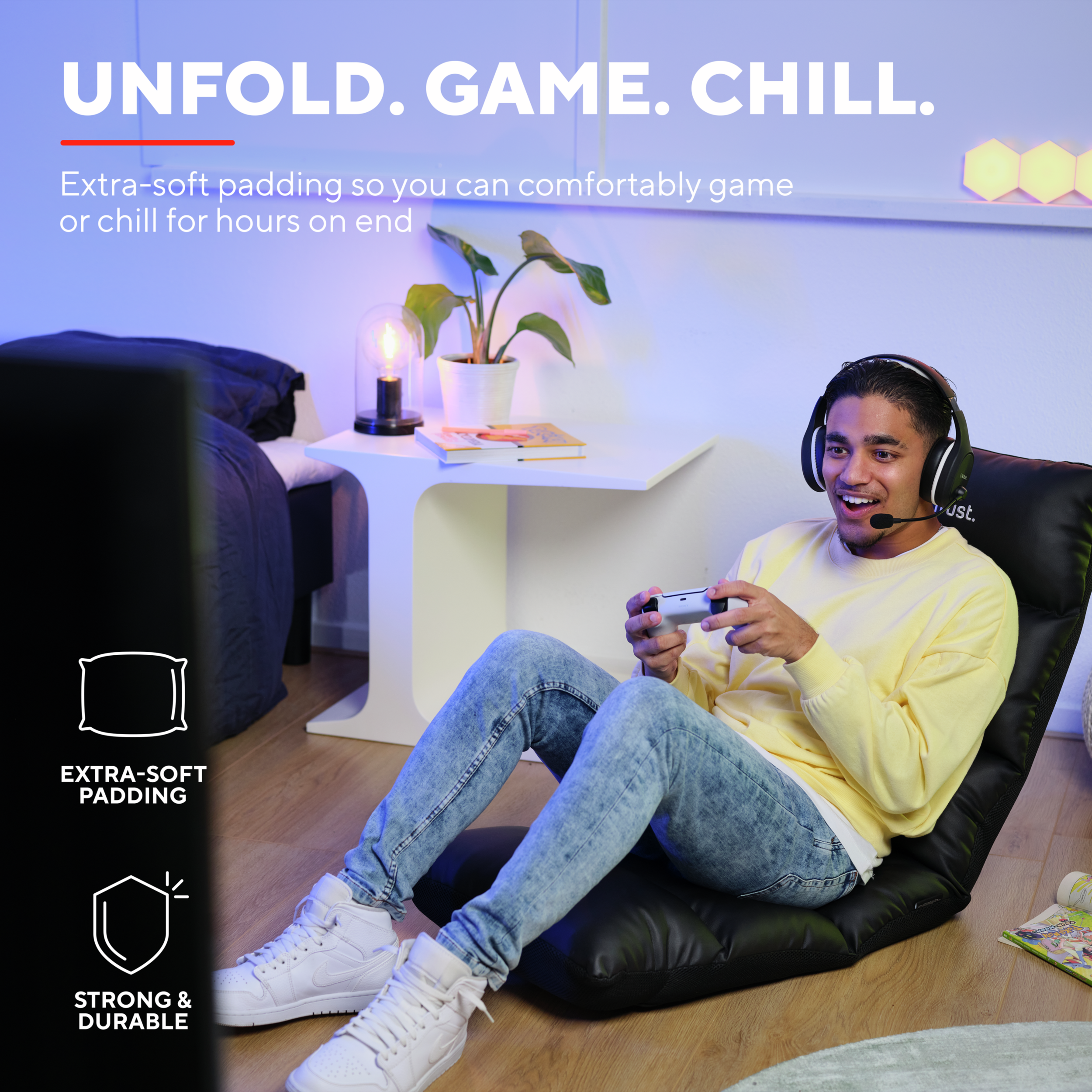 Mężczyzna grający na czarnym fotelu gamingowym w słuchawkach i z kontrolerem.