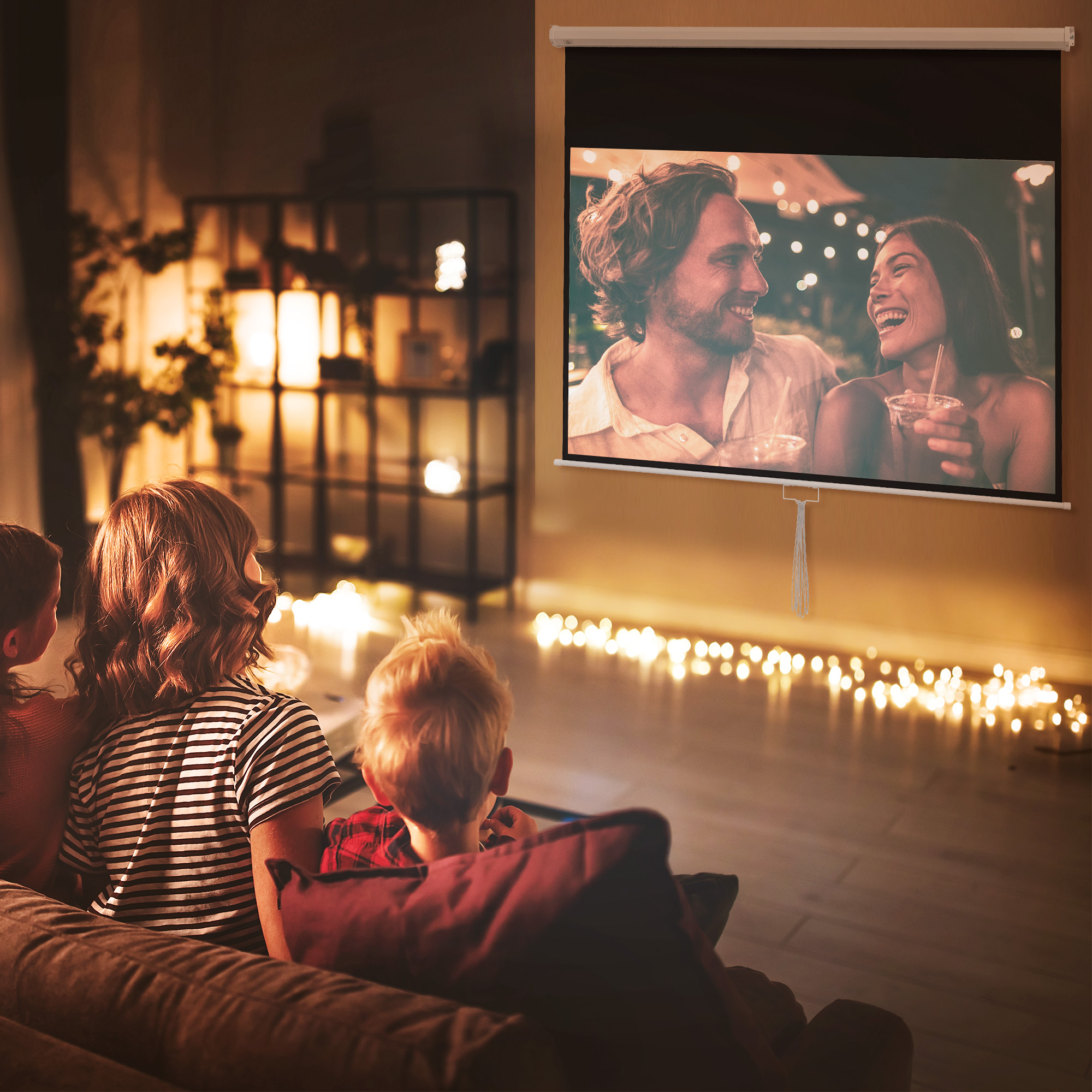 Persone guardano un film su uno schermo. Sono sedute su un divano, luci intorno.