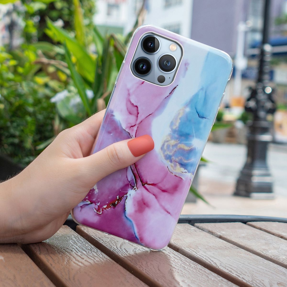 Eine Hand hält ein Telefon mit einer Handyhülle mit Marmormuster. Die Hülle ist rosa und blau.