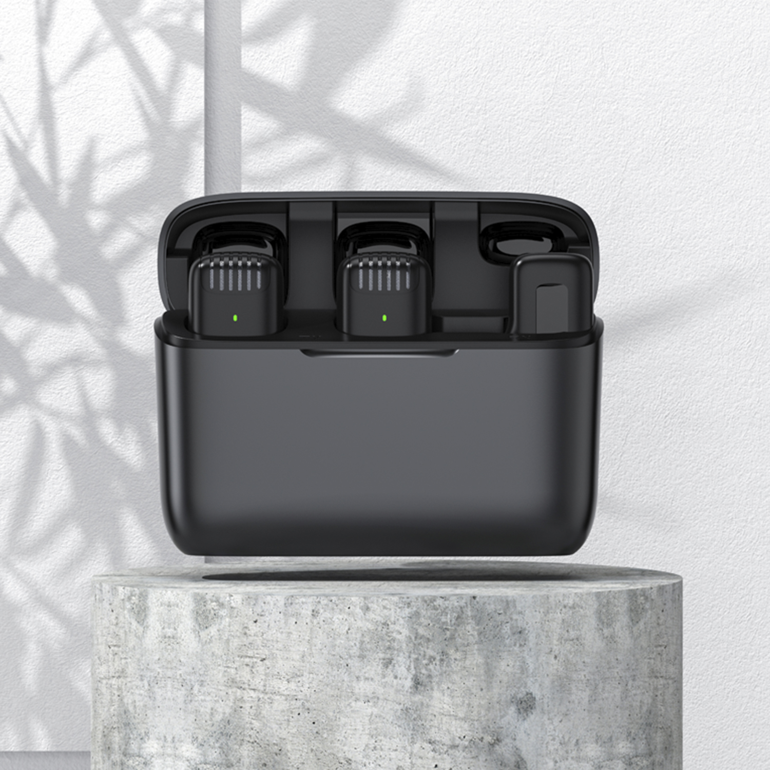 Un estuche de carga negro con tres micrófonos inalámbricos dentro. Está sobre un pedestal blanco.