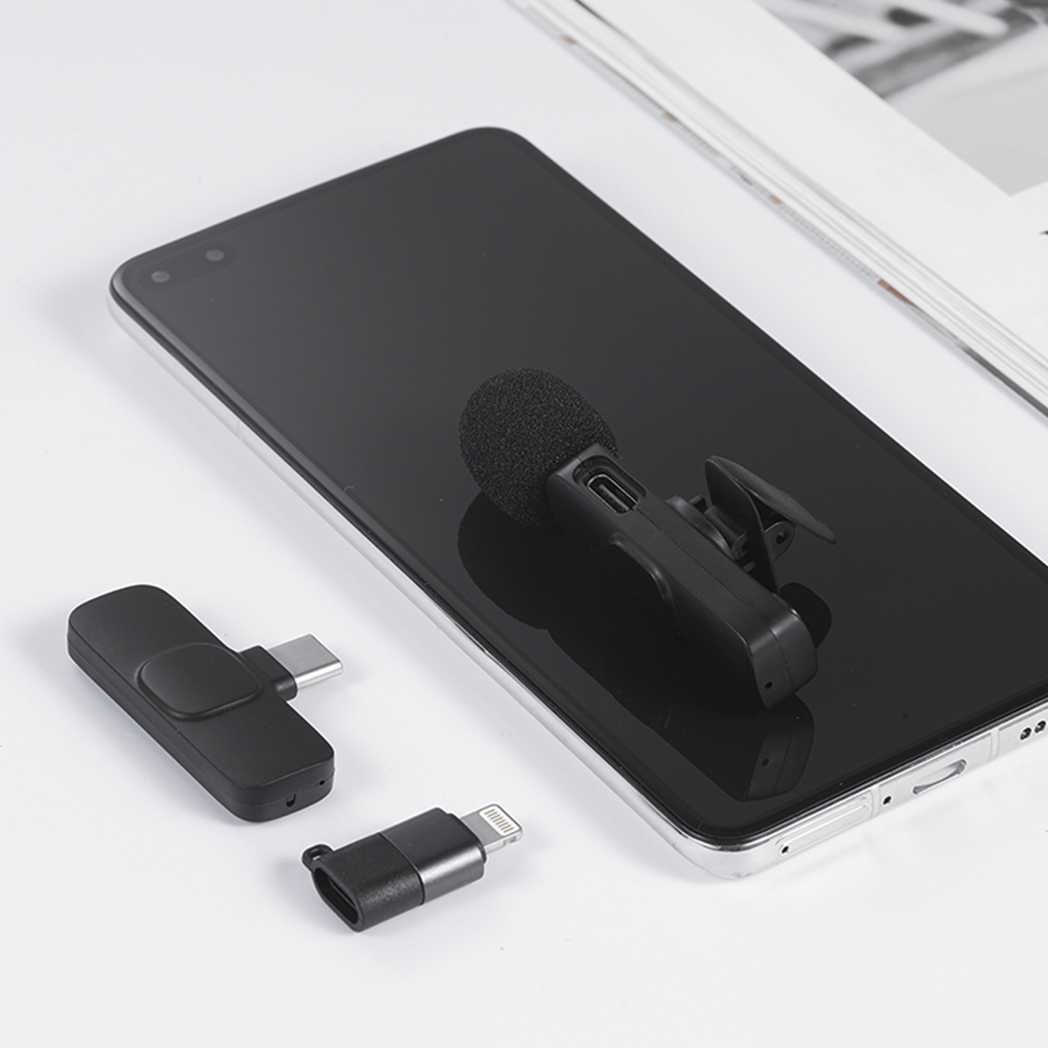 Un microfono nero agganciato a un telefono, con connettore USB-C e Lightning.