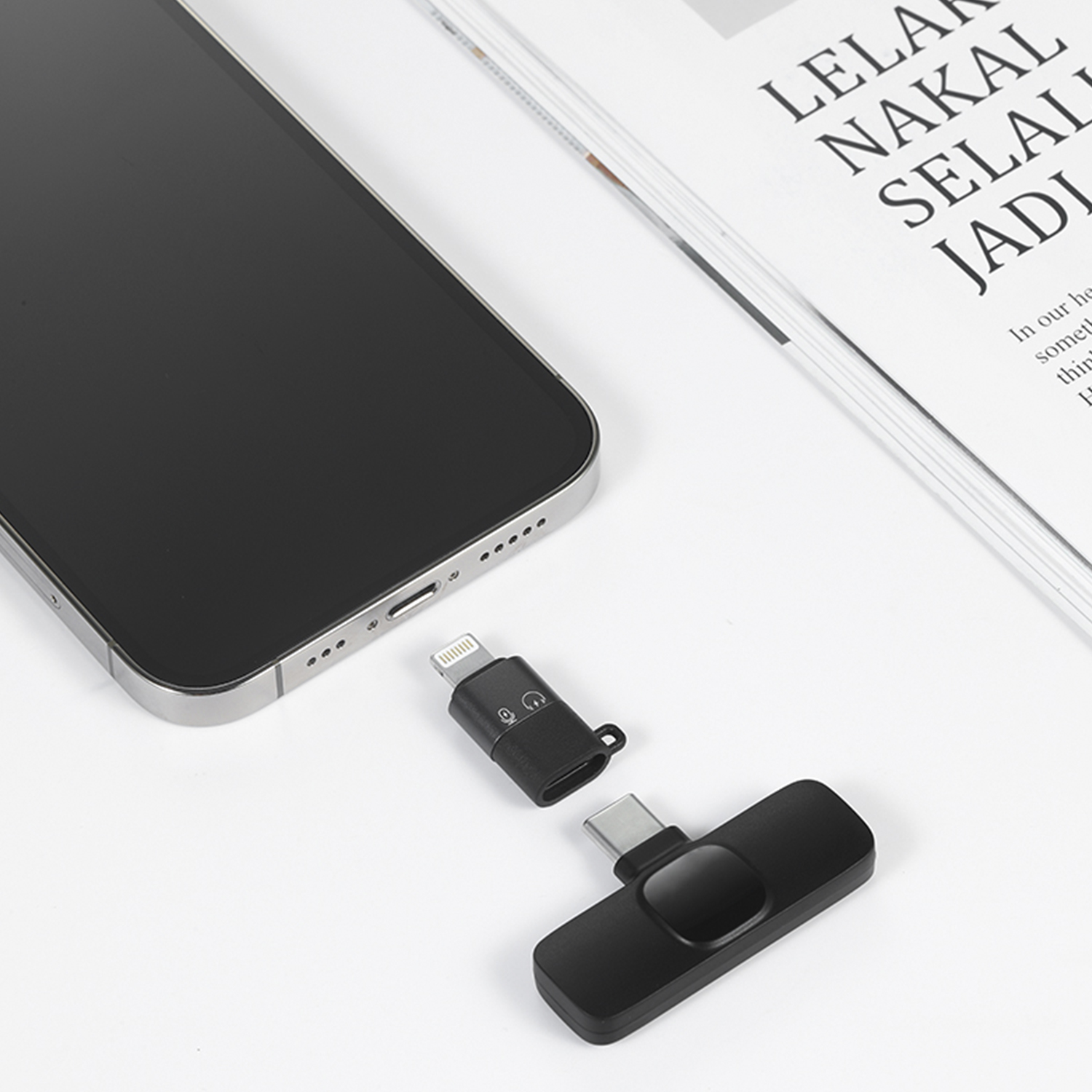 Telefono nero e due adattatori neri con connettori USB-C e Lightning.