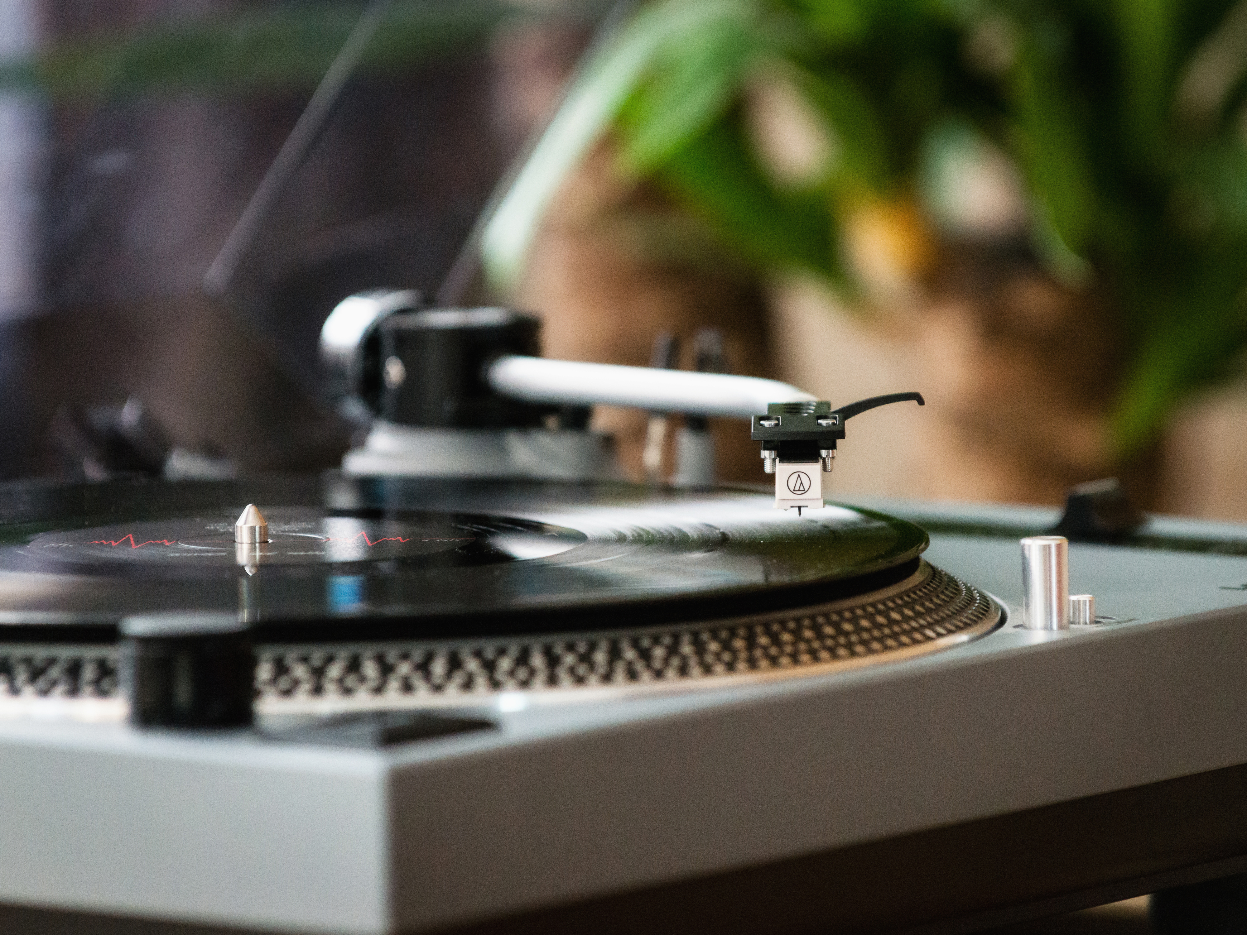 Tocadiscos con disco reproduciéndose, primer plano del brazo y la aguja.