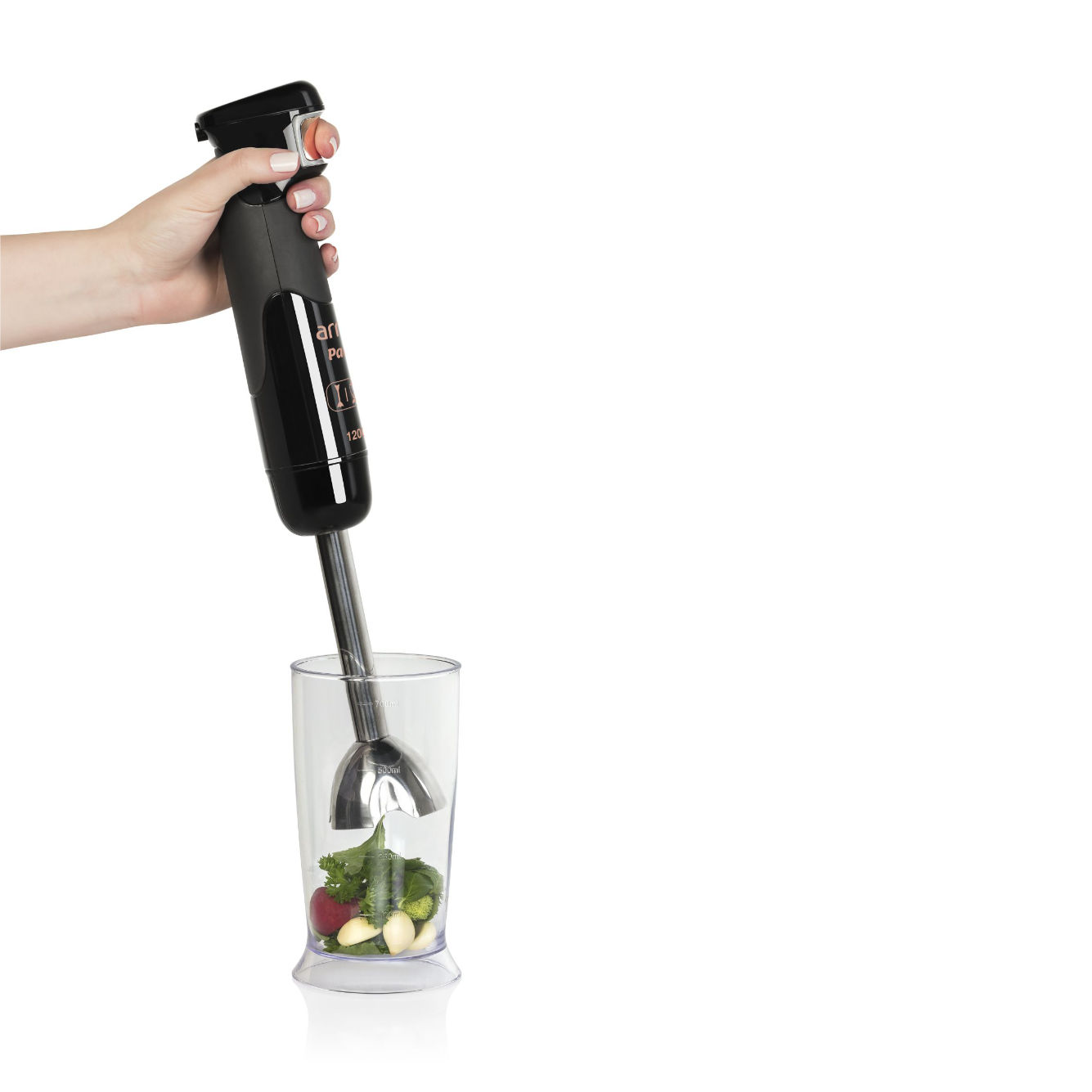 Hand hält einen schwarzen Stabmixer über einem Glas mit Zutaten. Weißer Hintergrund.