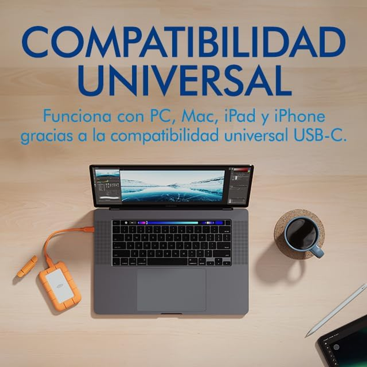 Laptop z monitorem pokazującym fotografię, kubek i tablet.