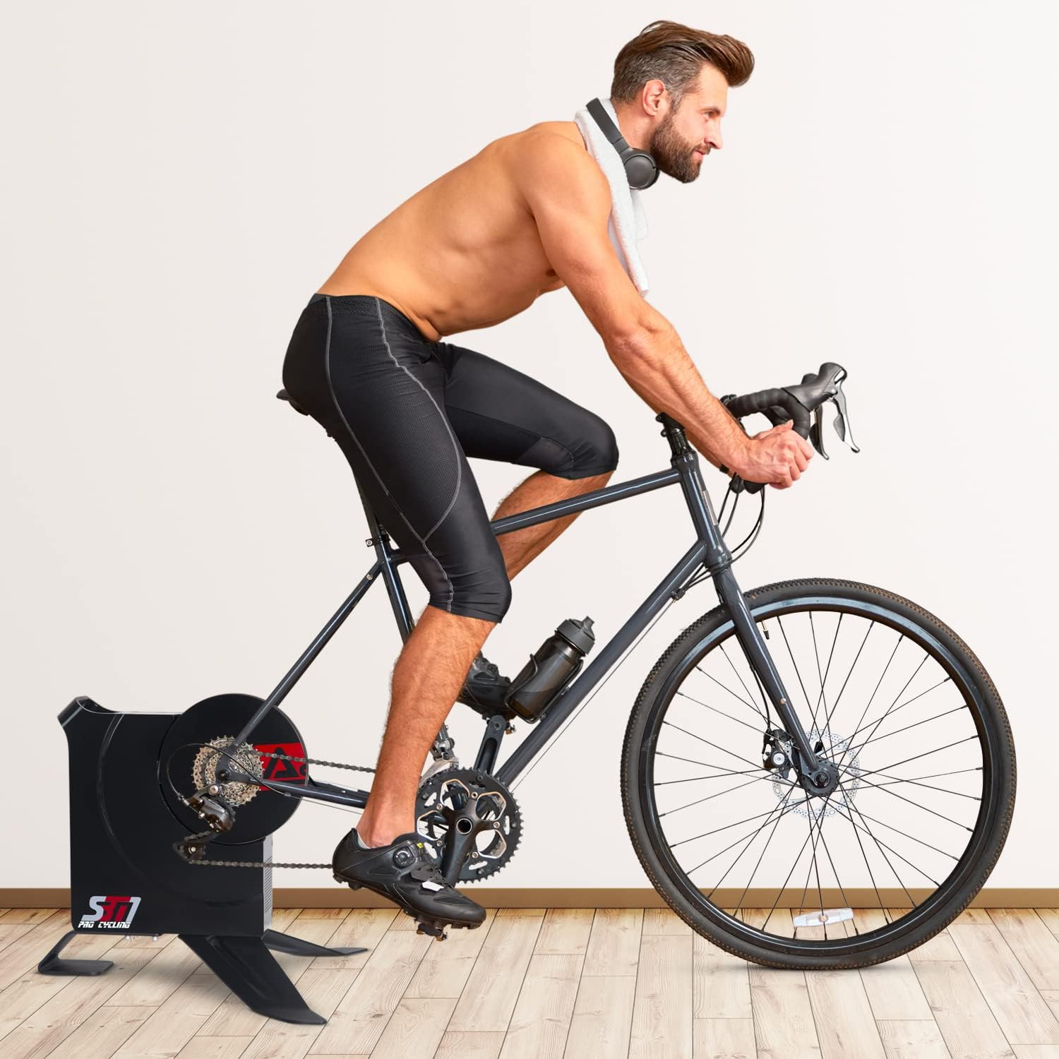Ein Mann auf einem Heimtrainer, mit einem Handtuch und einer Wasserflasche.