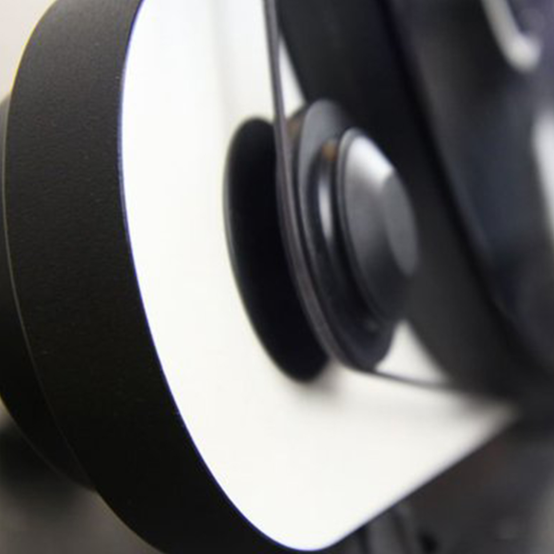 Close-up of a black object with a wheel and belt, showing a white surface.