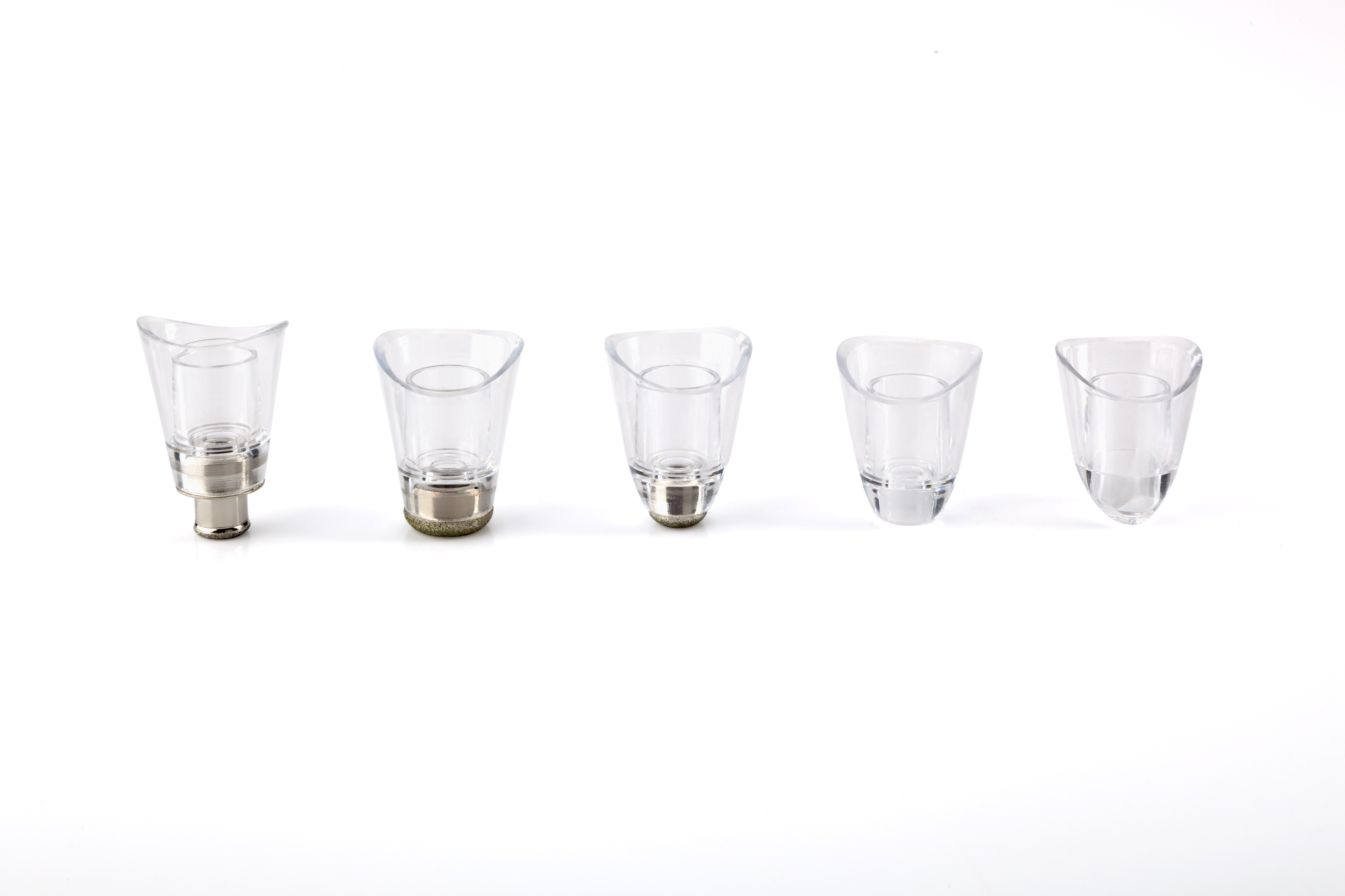 Pięć przezroczystych, plastikowych końcówek do odkurzacza. Różne kształty, białe tło.