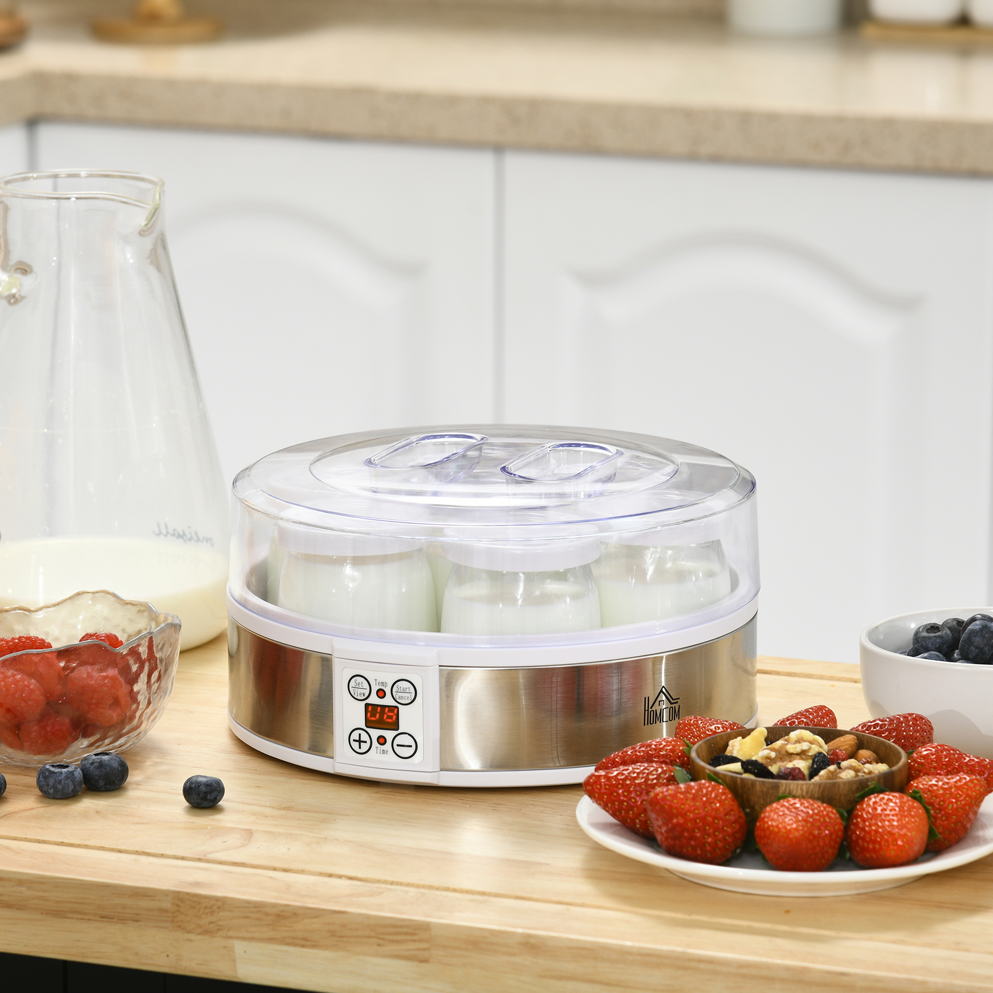 Yogurtera con tarros. Fresas y arándanos. Mesa de madera. Cocina.