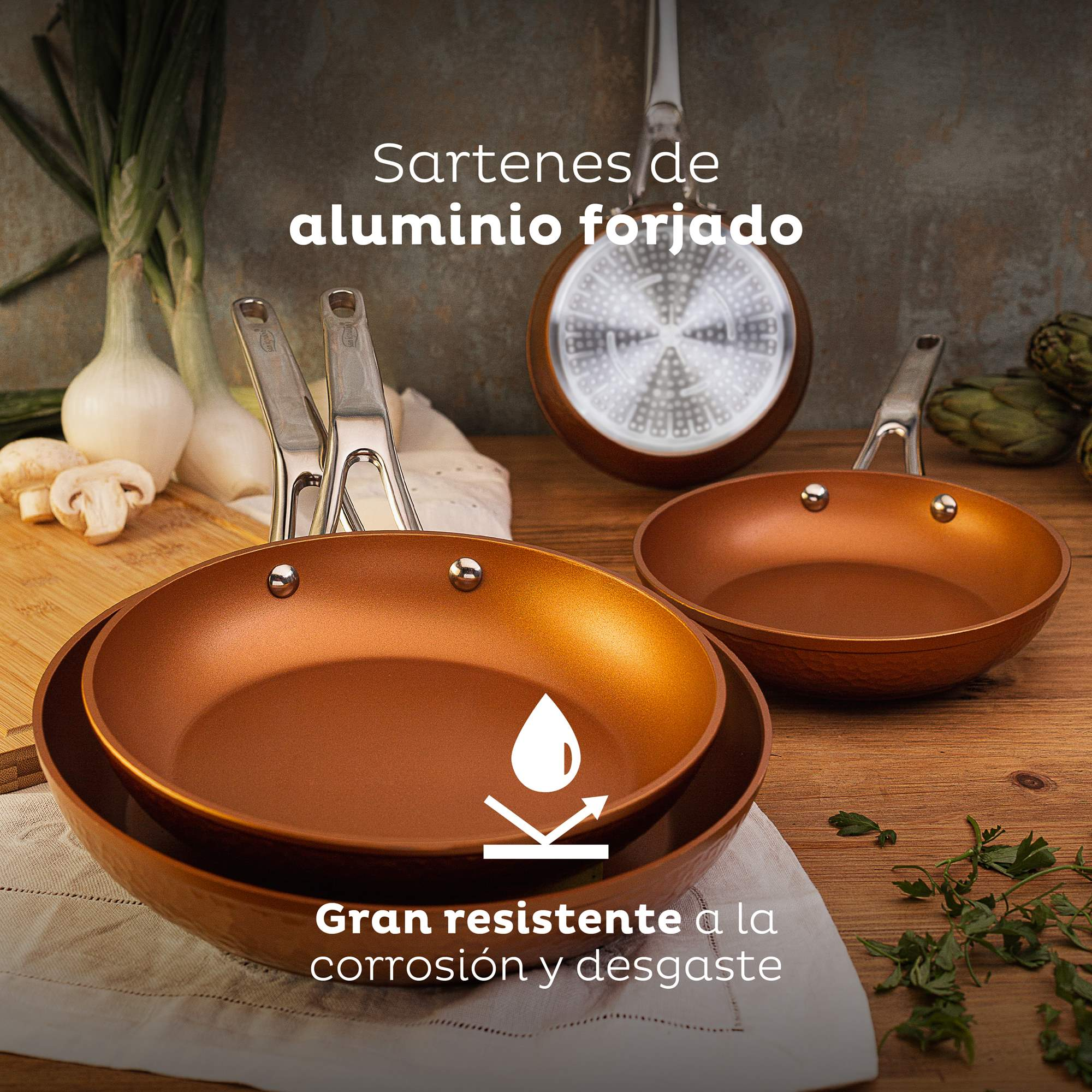 Sartenes color cobre con mangos metálicos sobre mesa de madera con cebollas y champiñones.