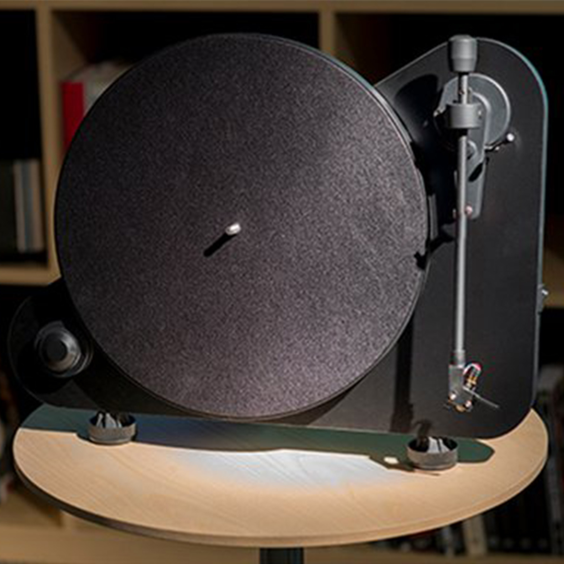 Un giradischi nero su un supporto color legno, con un disco nero, su uno sfondo sfocato.