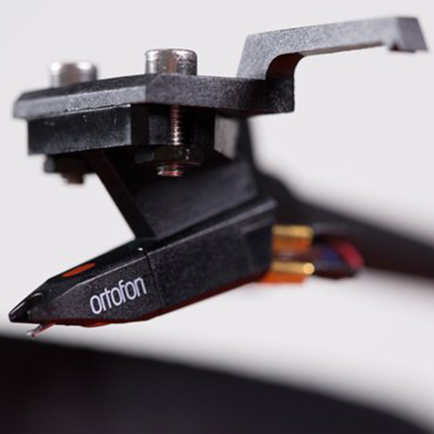 A close-up of a black turntable cartridge with the word 'ortofon' on it.