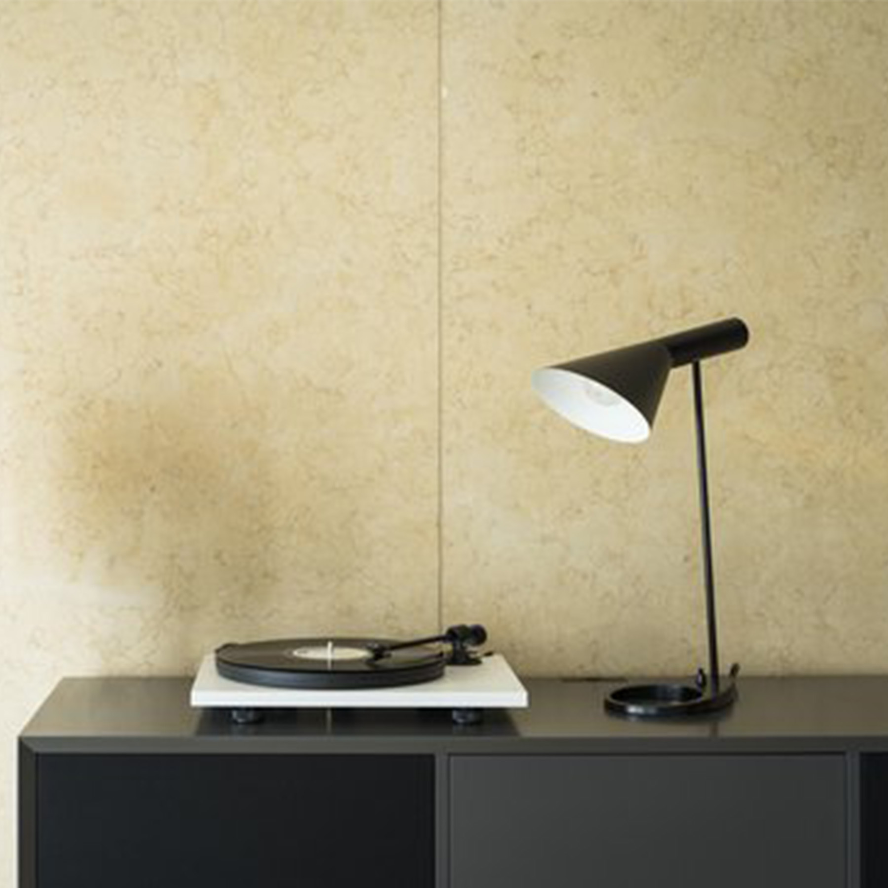 Un giradischi e una lampada in bianco e nero su un mobile grigio scuro.