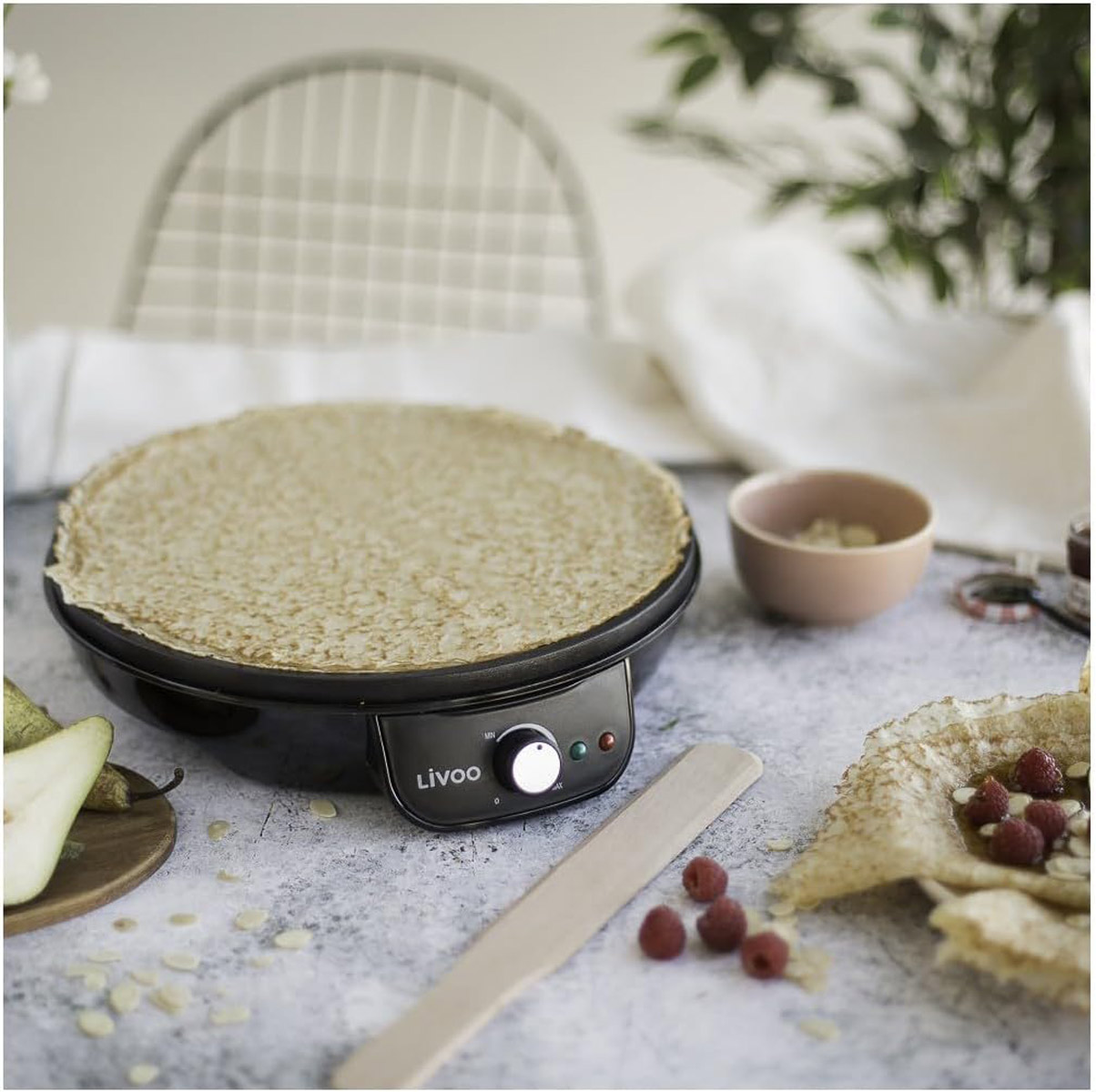 Maszyna do naleśników z upieczonym naleśnikiem. Składniki wokół.