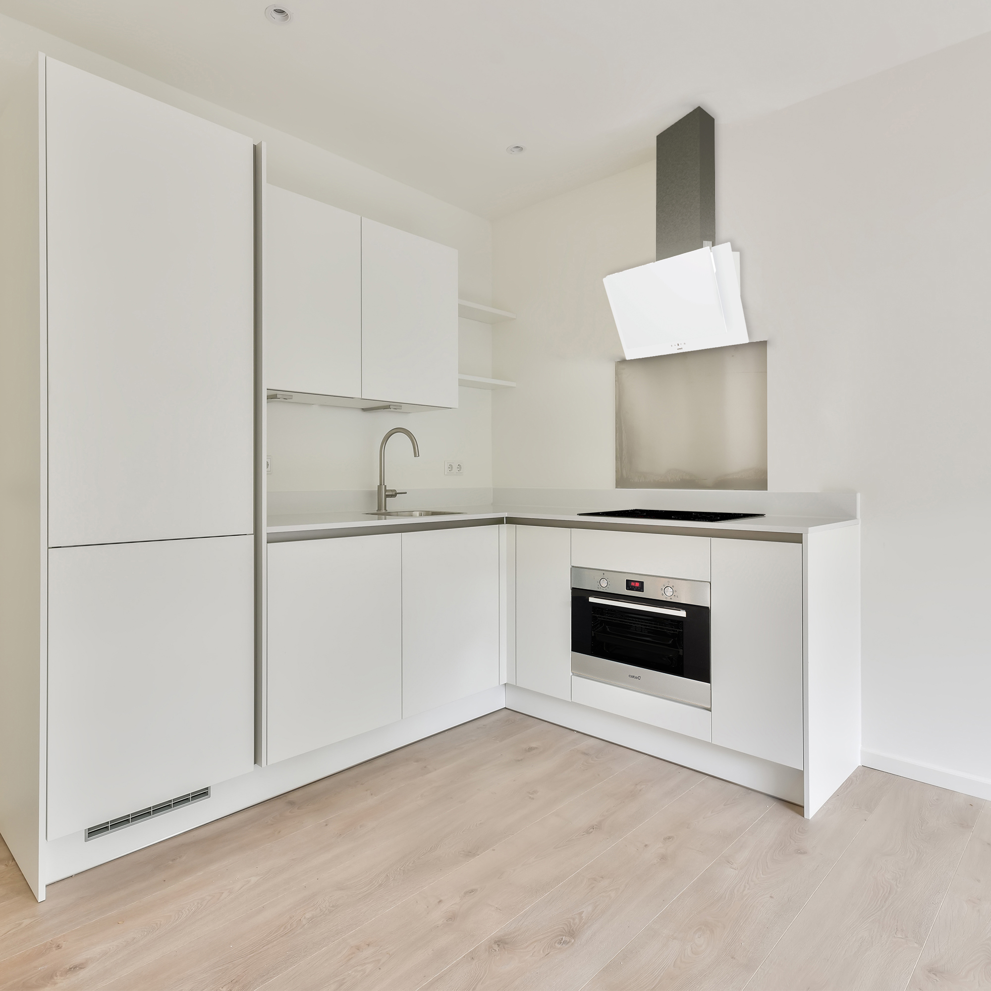 Una cocina blanca moderna con gabinetes blancos, horno de acero inoxidable y pisos de madera.