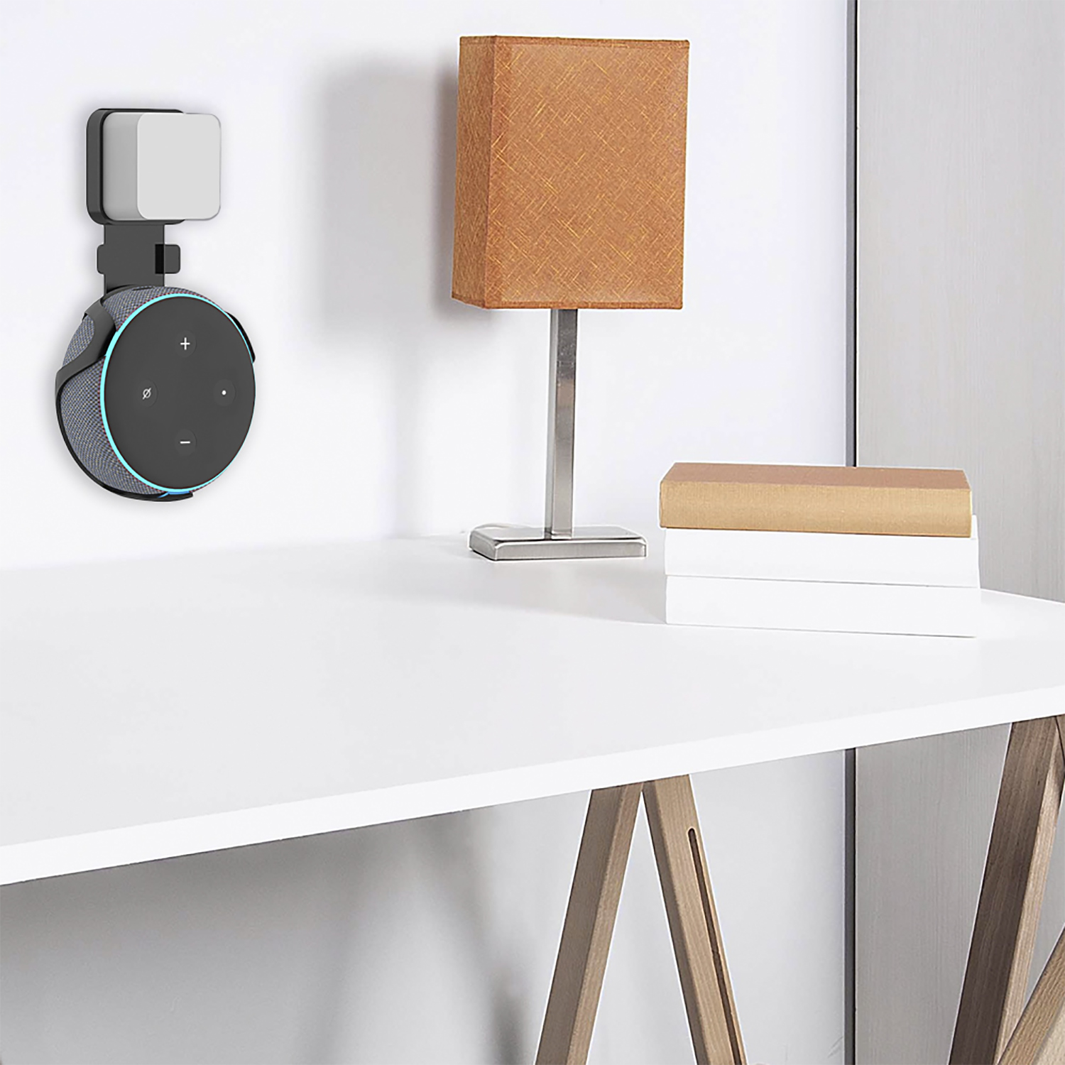 Un Echo Dot e una luce sono montati su un muro, con una lampada e libri su una scrivania bianca.