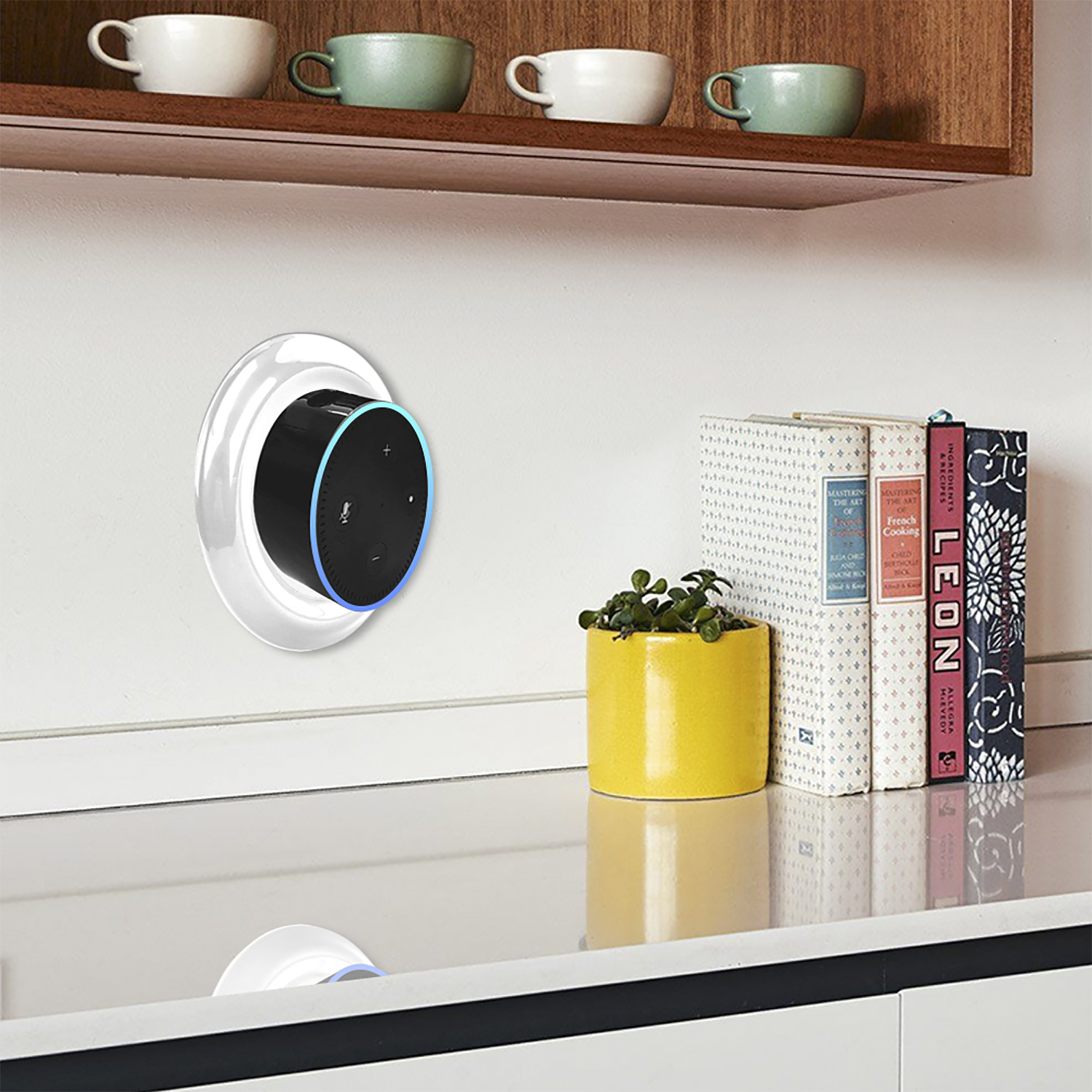 Un Echo Dot su supporto a parete. Libri e un vaso giallo sul bancone. Tazze su uno scaffale.