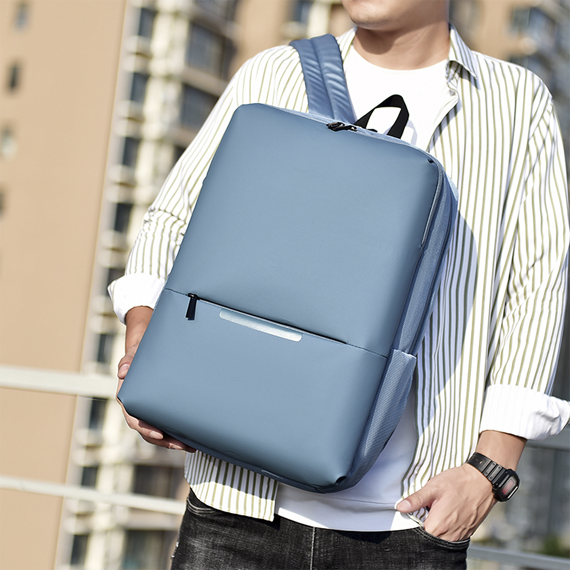Uomo con zaino blu su camicia a righe bianche.