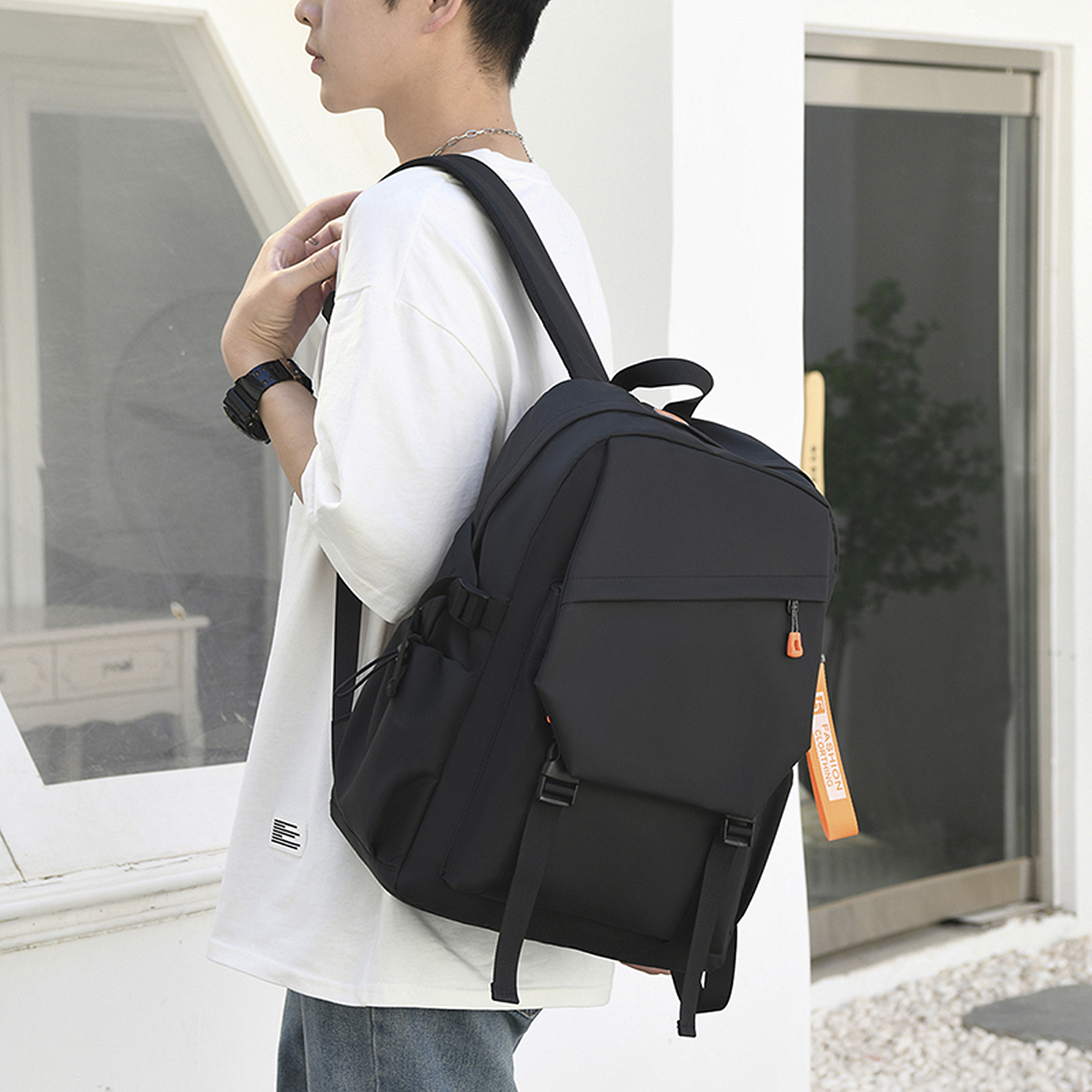 Uomo con camicia bianca e zaino nero. La borsa è nera con cinghie e fibbie.