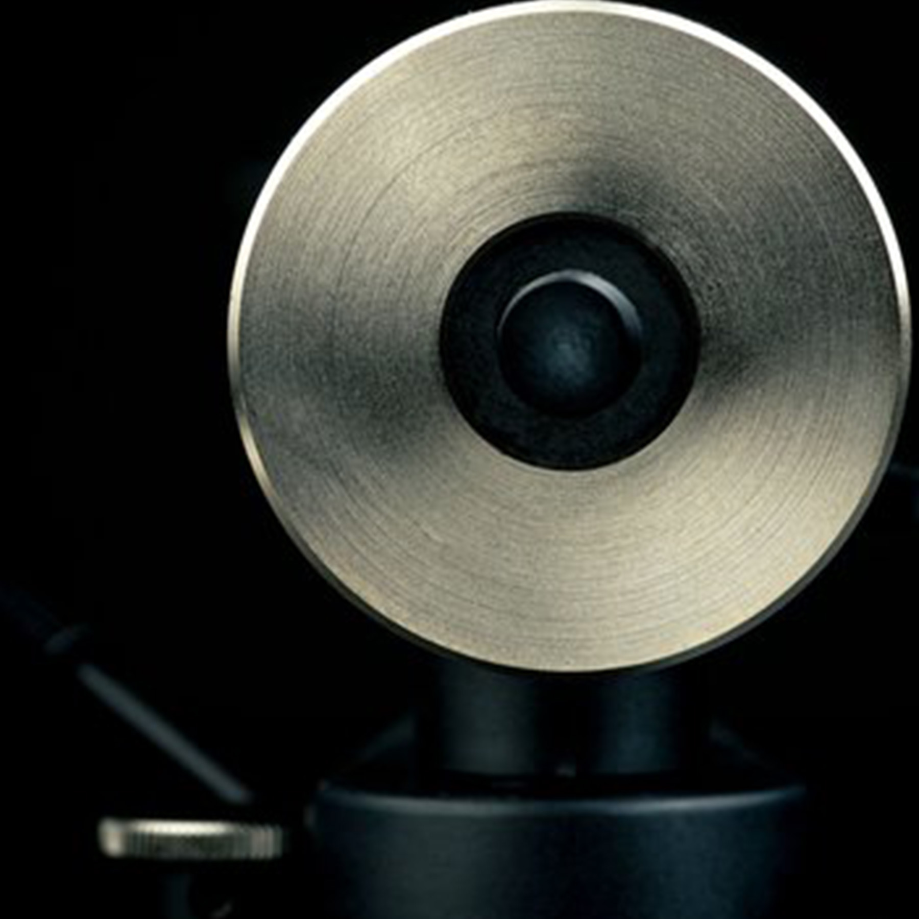 A close-up of a metal part of a device. It is circular, with a black center.