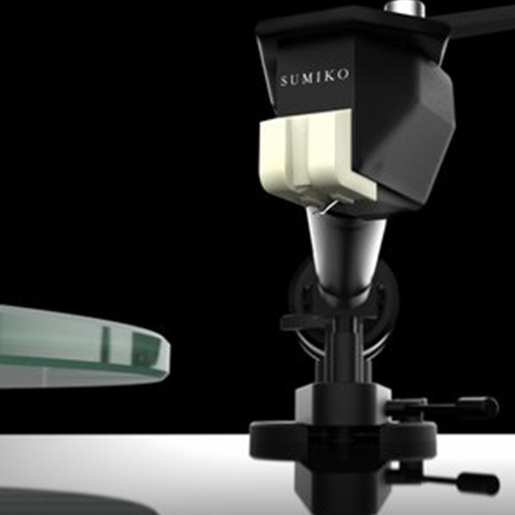Close-up of a turntable cartridge with a black body and white stylus. Black background.