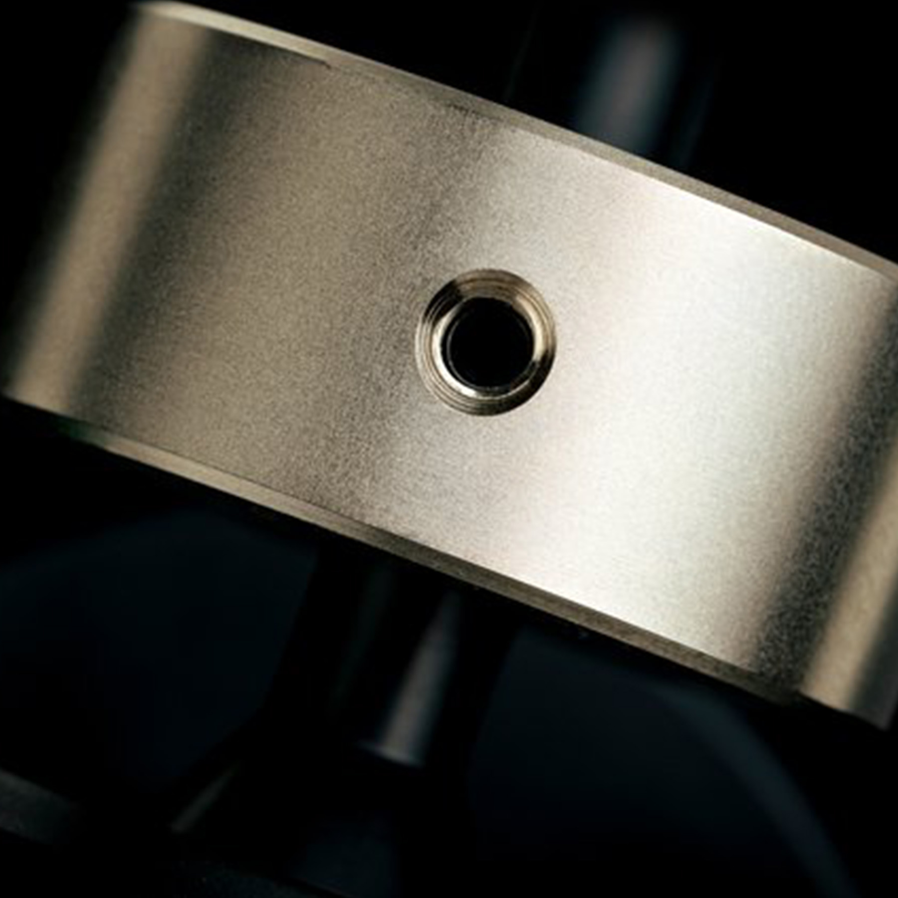 Close-up of a metallic ring with a hole in the center. The surface reflects light.