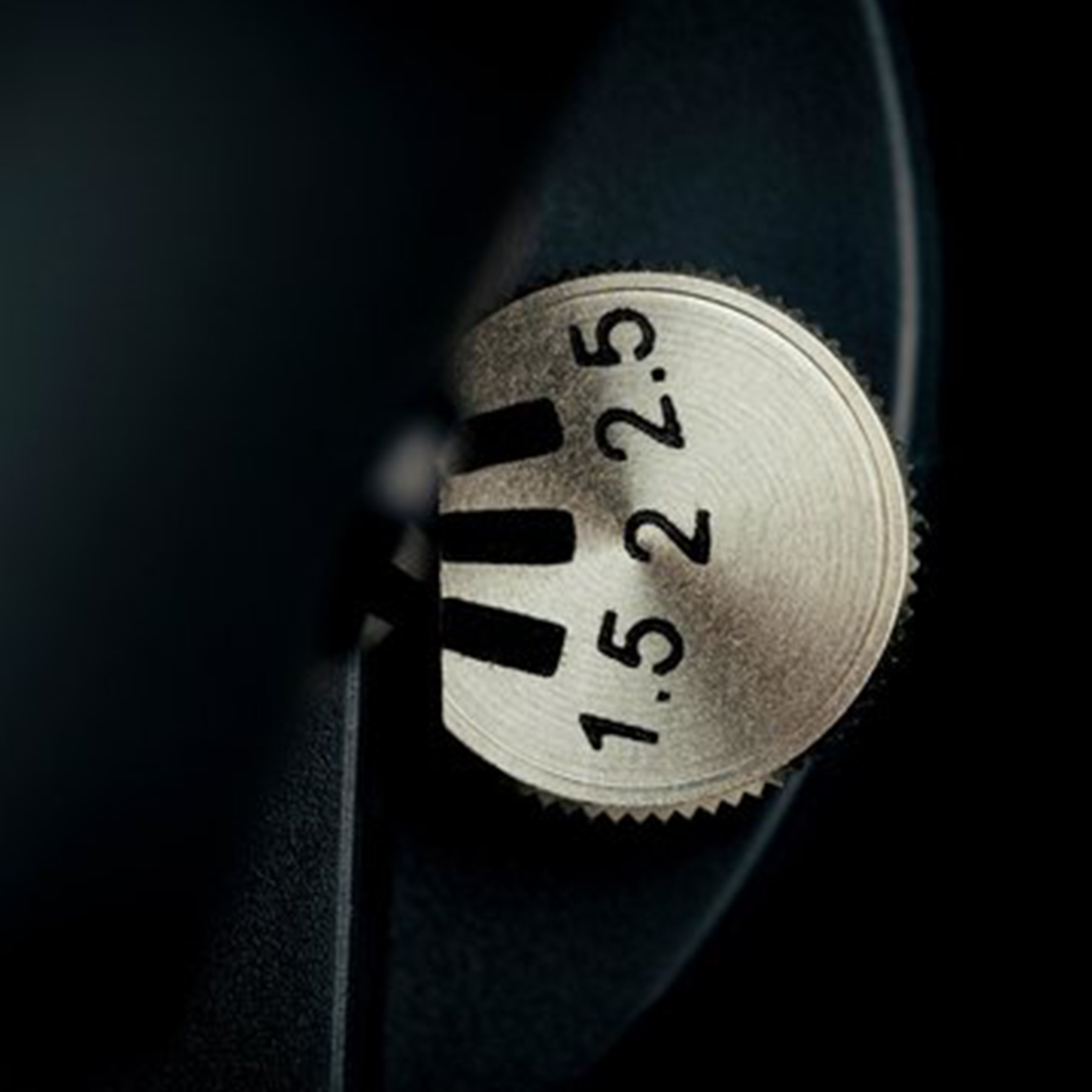 A silver dial with numbers, 1.5, 2, and 2.5, with a black background.