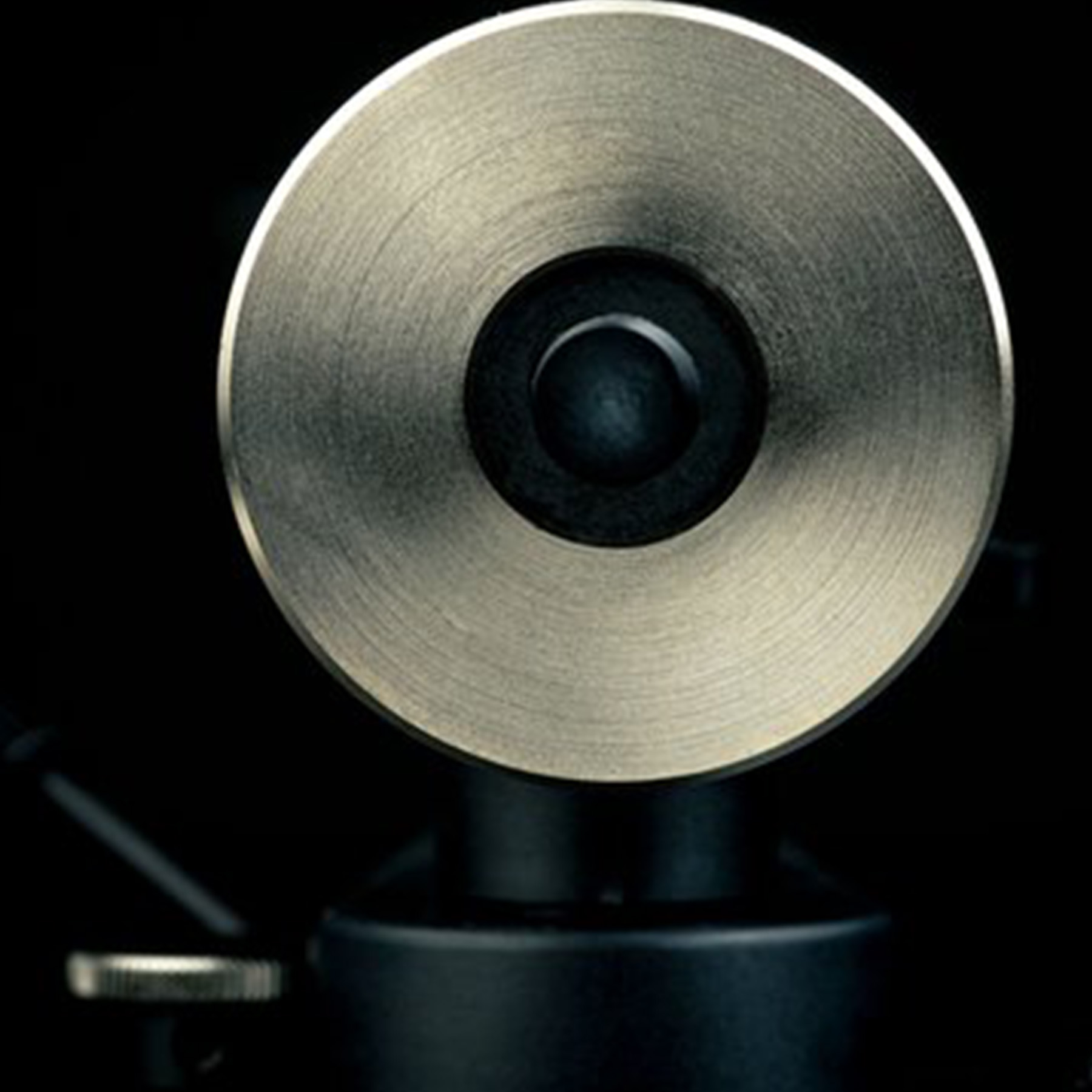 A close-up of a silver, disc-shaped object with a black center on a dark background.