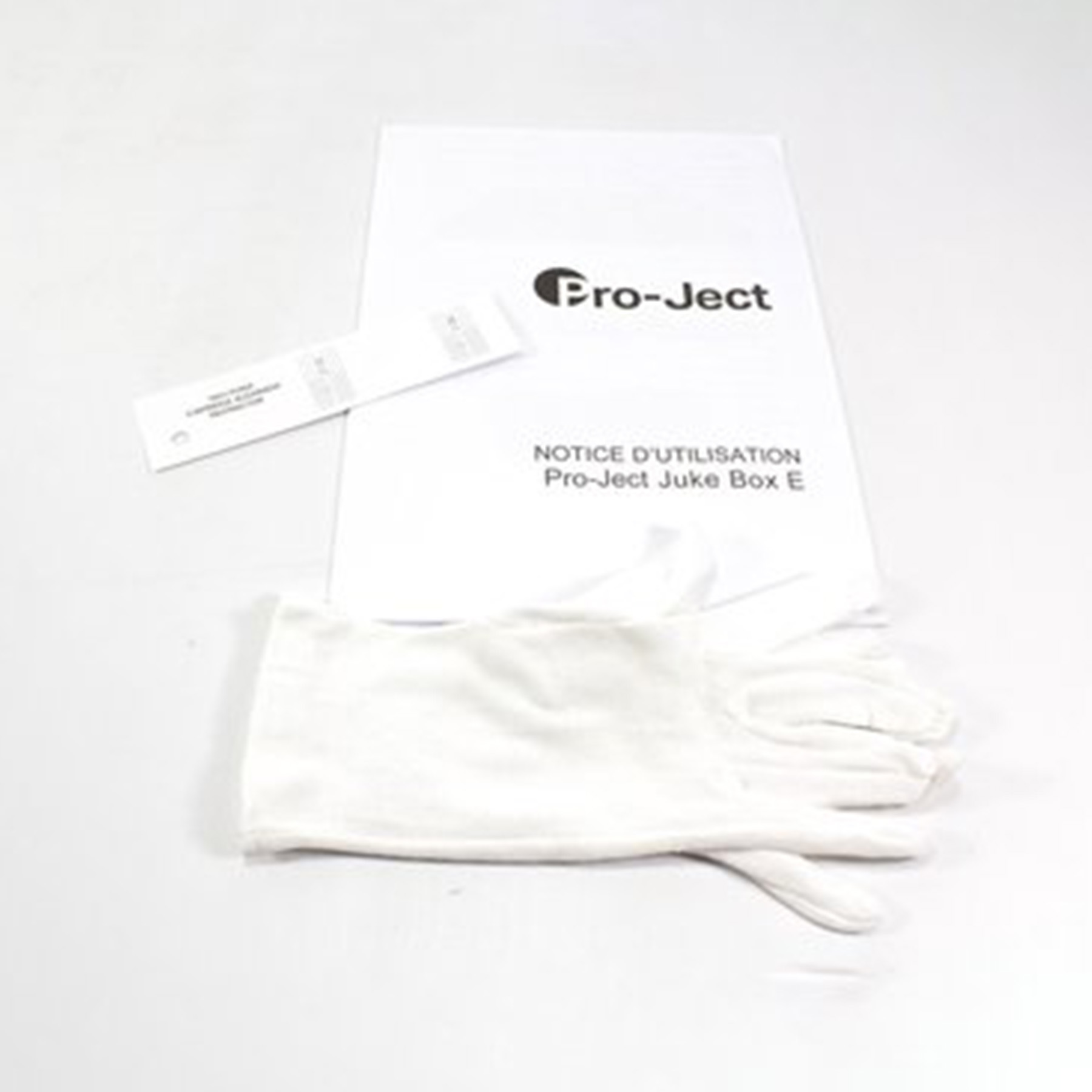 Białe rękawiczki i instrukcja obok instrukcji Pro-Ject na białej powierzchni.