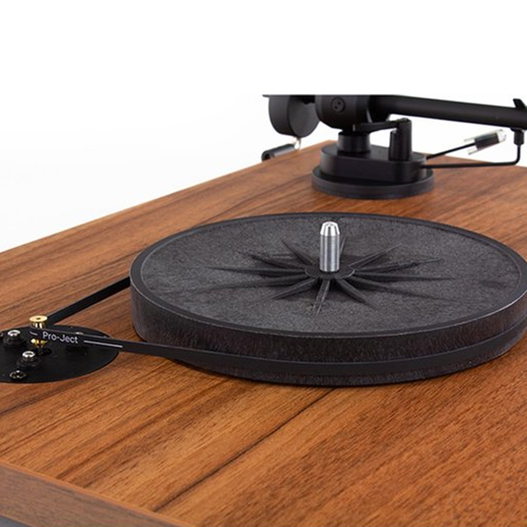 Plattenspieler mit schwarzem Vinyl. Holzmaserung im Hintergrund. Pro-Ject Logo sichtbar.