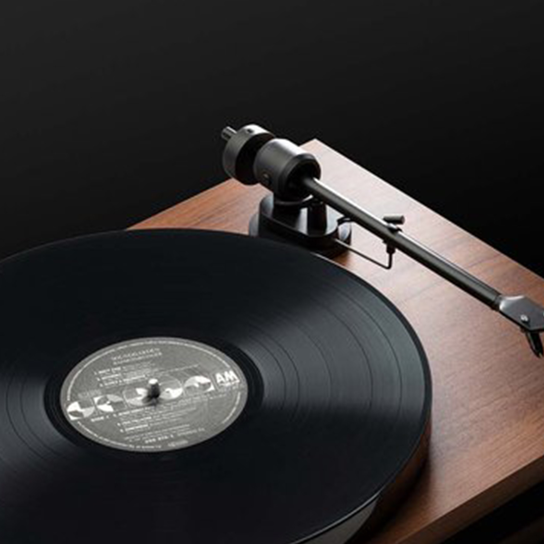 Nahaufnahme eines Plattenspielers mit einer schwarzen Vinyl-Schallplatte. Der Tonarm ist sichtbar.