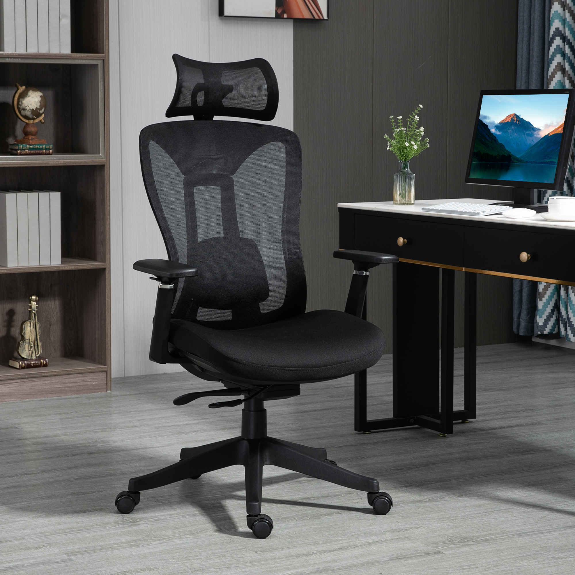 Silla de oficina de malla negra. Con reposacabezas, reposabrazos y ruedas. Escritorio negro al fondo.