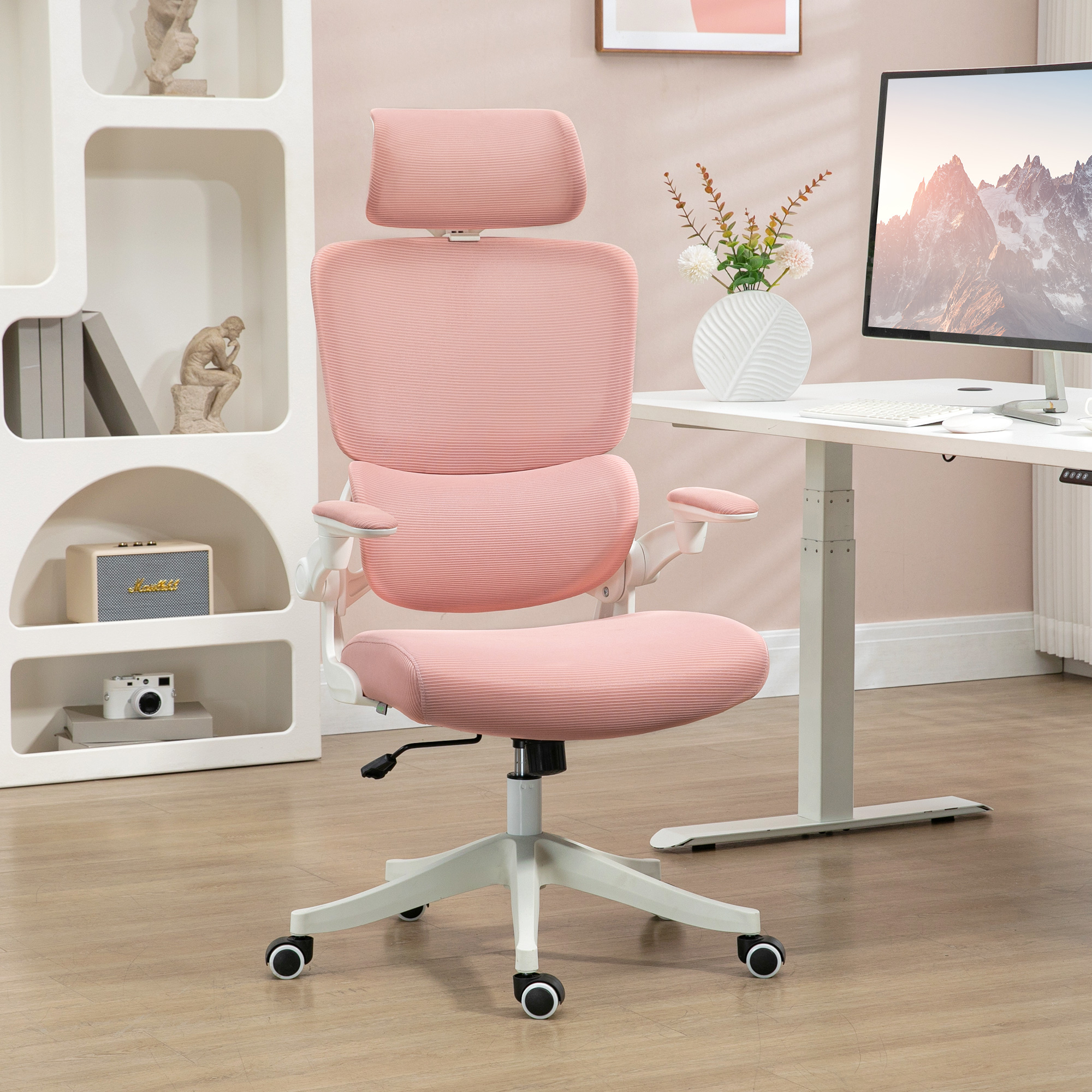 Silla de oficina rosa, marco blanco, reposacabezas ajustable, cerca de escritorio y monitor blancos.