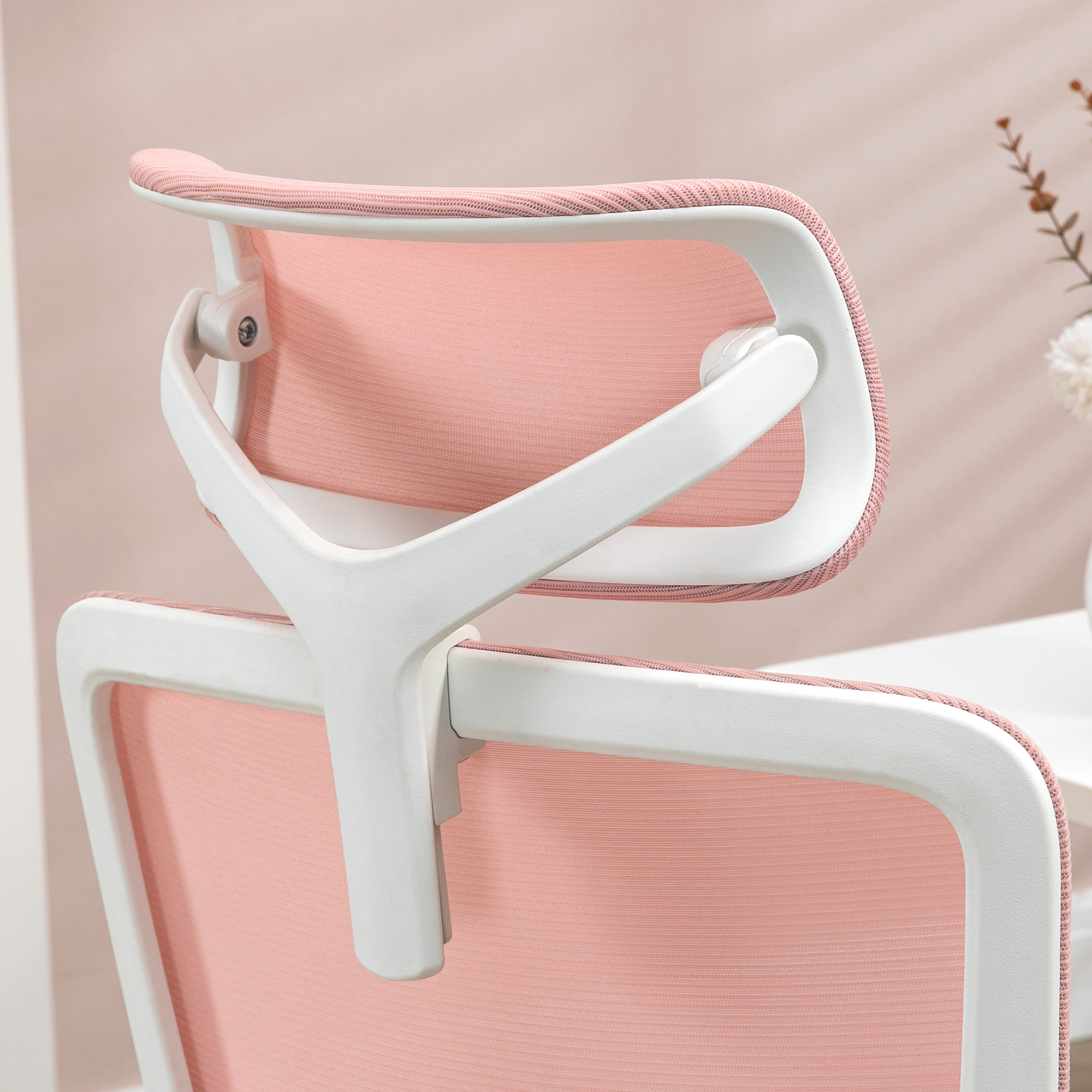 La parte trasera de una silla de oficina ergonómica. Tiene un respaldo de malla rosa y un marco blanco.