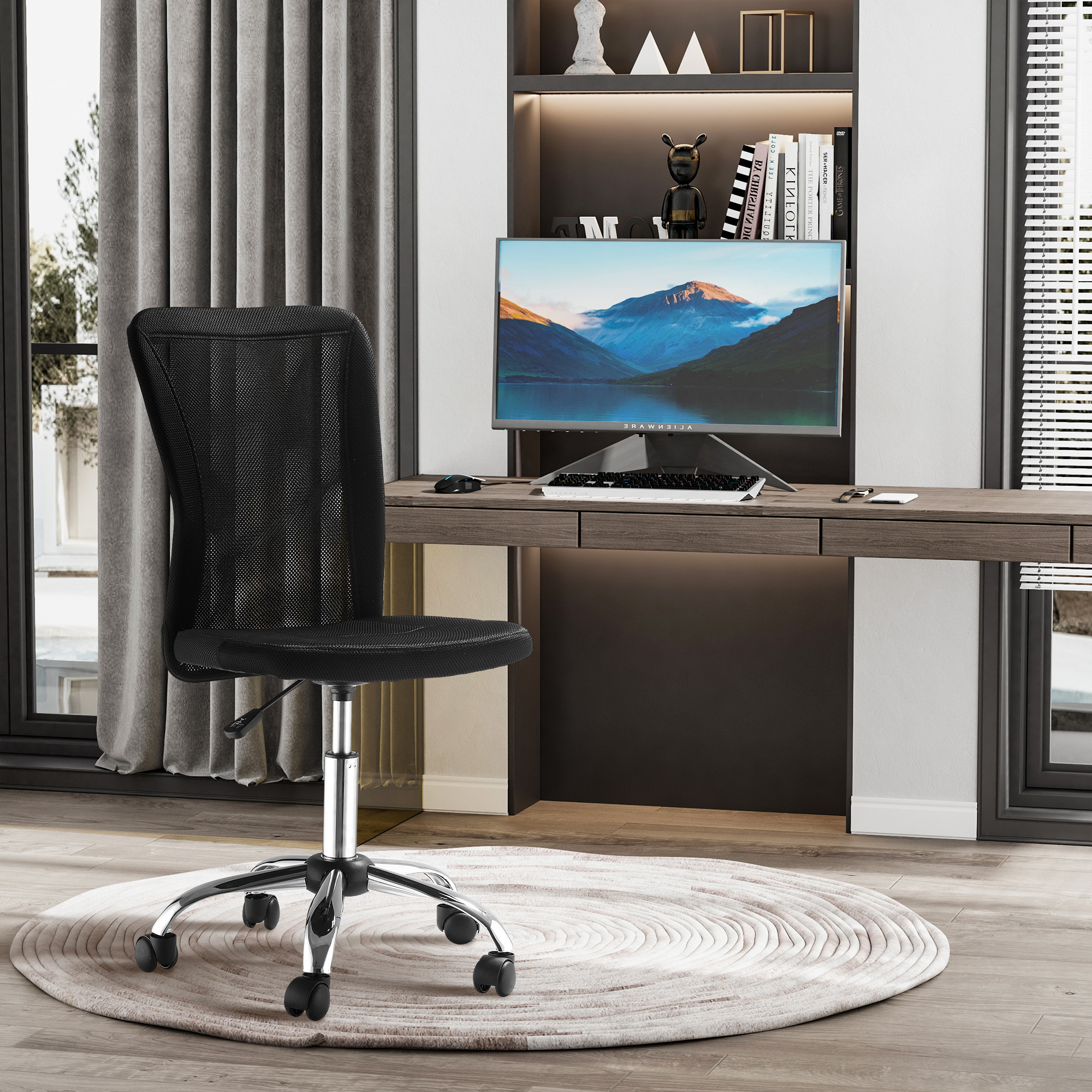 Una oficina con una silla de malla negra, un escritorio, un monitor de computadora y una alfombra circular en primer plano.