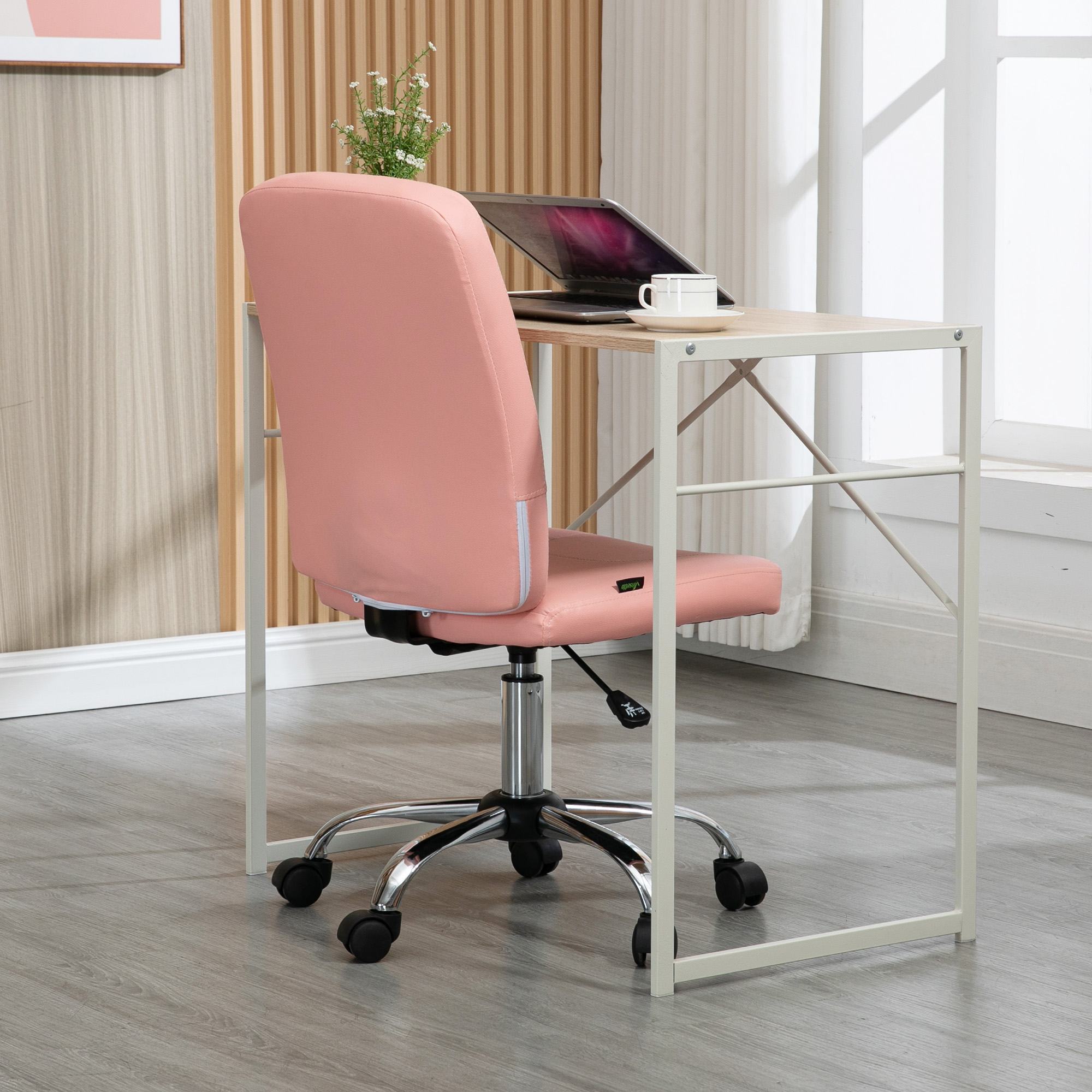 Configuración de oficina: Silla rosa, portátil y escritorio. Una taza en el escritorio.