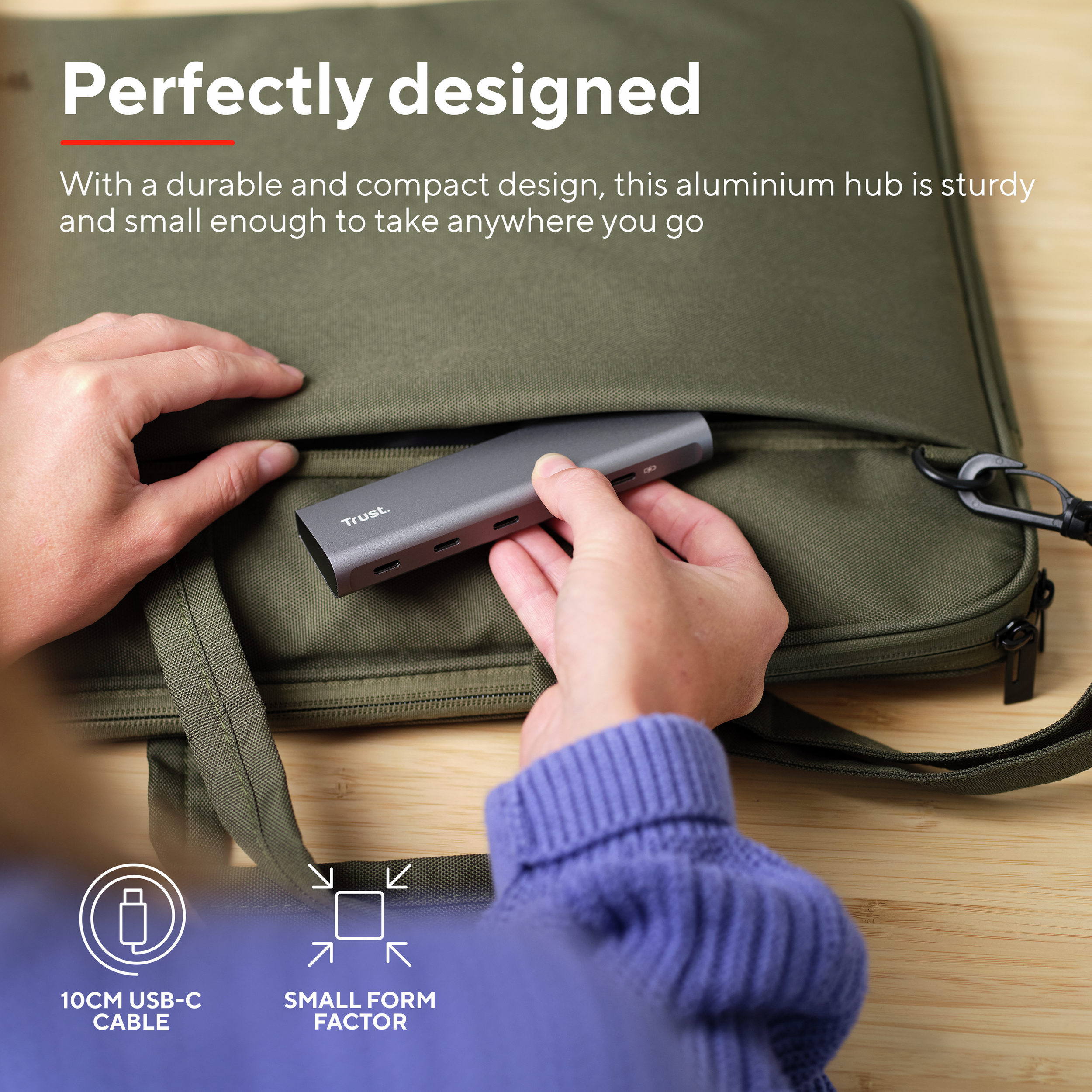 Un hub USB argentato con un cavo collegato, tenuto da una persona, su una superficie di legno.